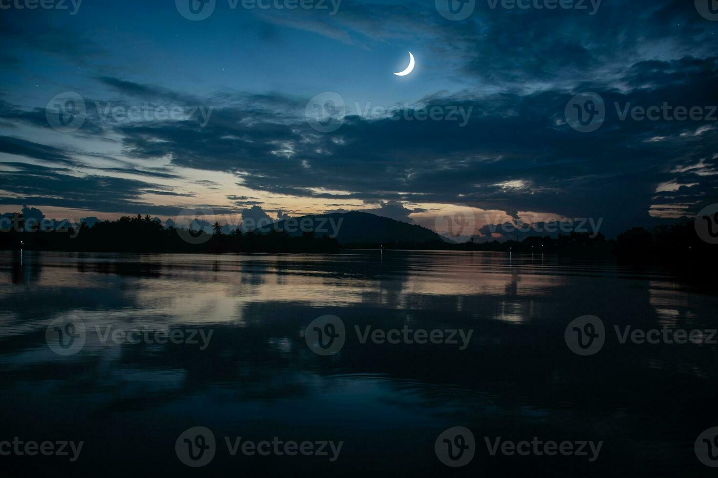 See the Islamic moon in the night sky. The evening sky and the vast river in darkness are beautiful. The crescent moon concept, the symbol of Islam, begins the month of Ramadan, eid al fitr photo