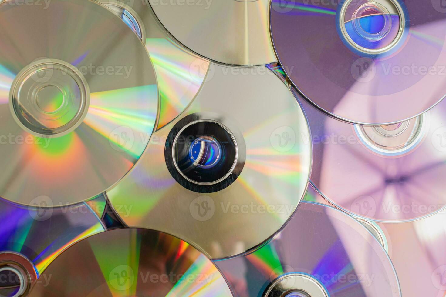 Many old CDs represent technology from the 90s. Stacks of CDs, old songs and old movies. which had been used before and placed on a white table. closeup, selective focus photo