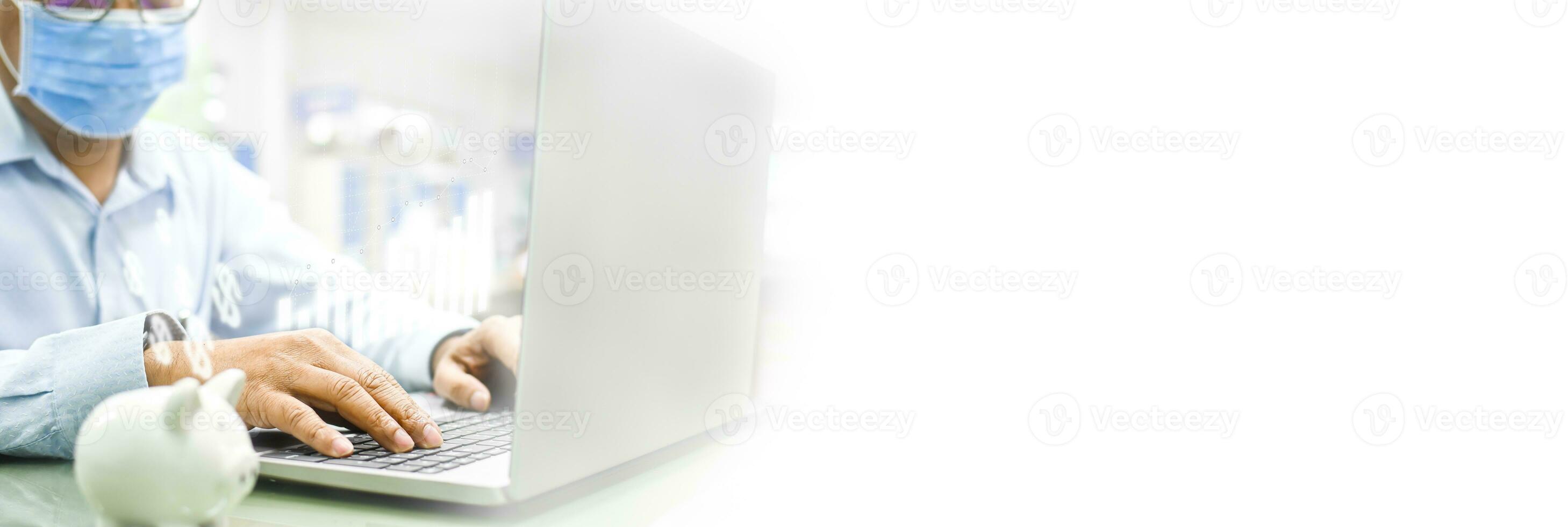 Take a closeup of the male hands is working on a laptop on the glass table. Young man wearing a face mask protect coronavirus or covid 19. Copyspace on right for the design. White Blurred background. photo