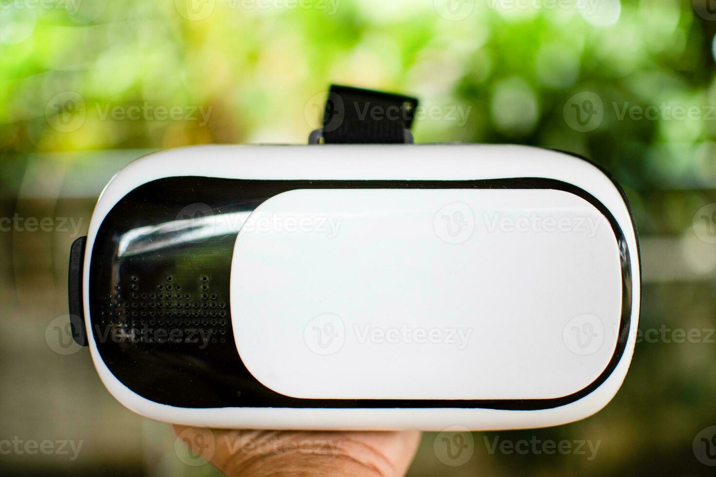 Male hand holding Virtual reality VR white and black. Man VR plays alone. Closeup, Blurred background. photo