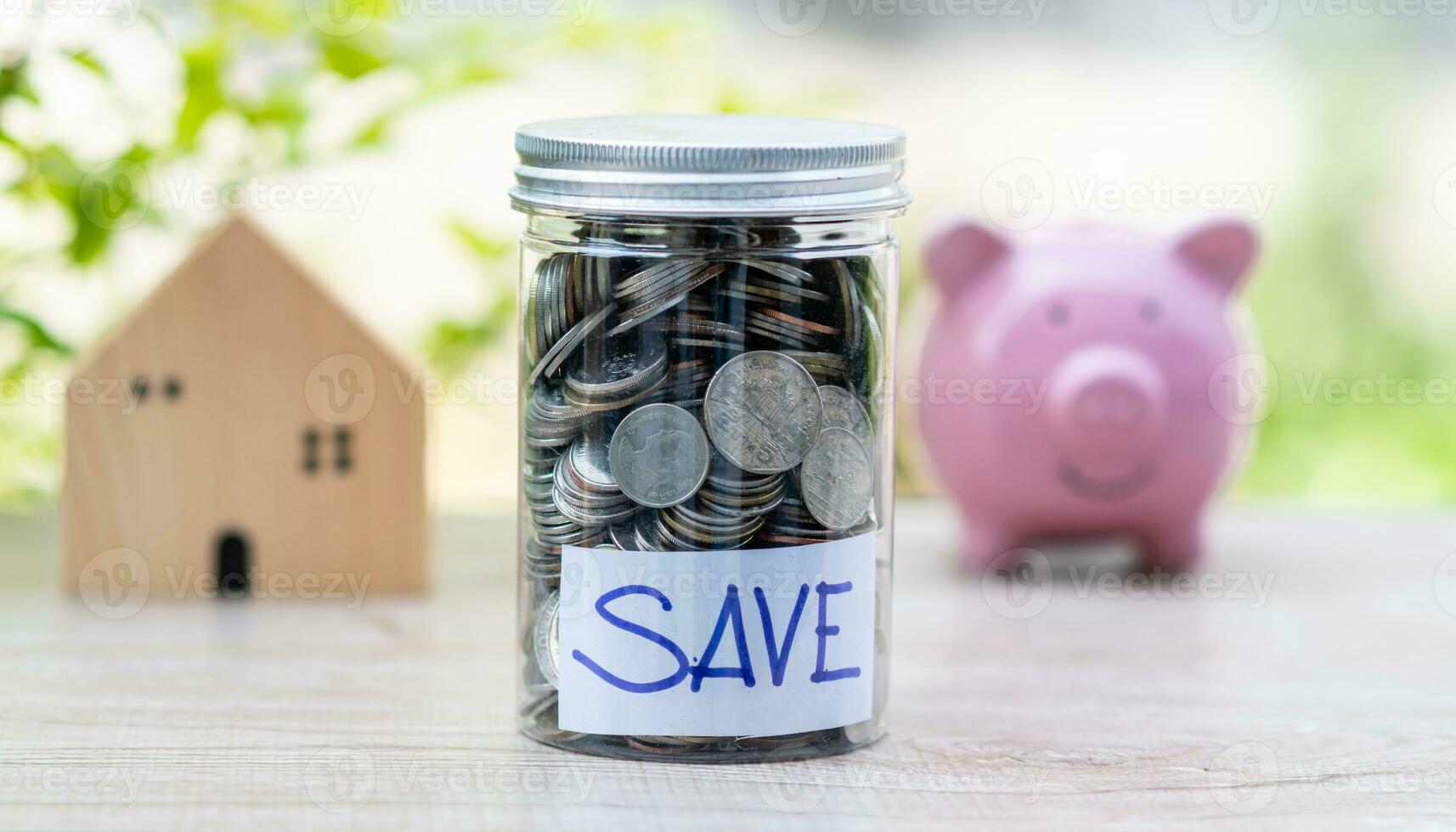 un tarro de monedas en el mesa, concepto, negocio, finanzas, bancario, ahorro, real bienes, inversión. nadie, No gente, borroso fondo, modelo de madera casa y rosado cerdo cerdito banco foto