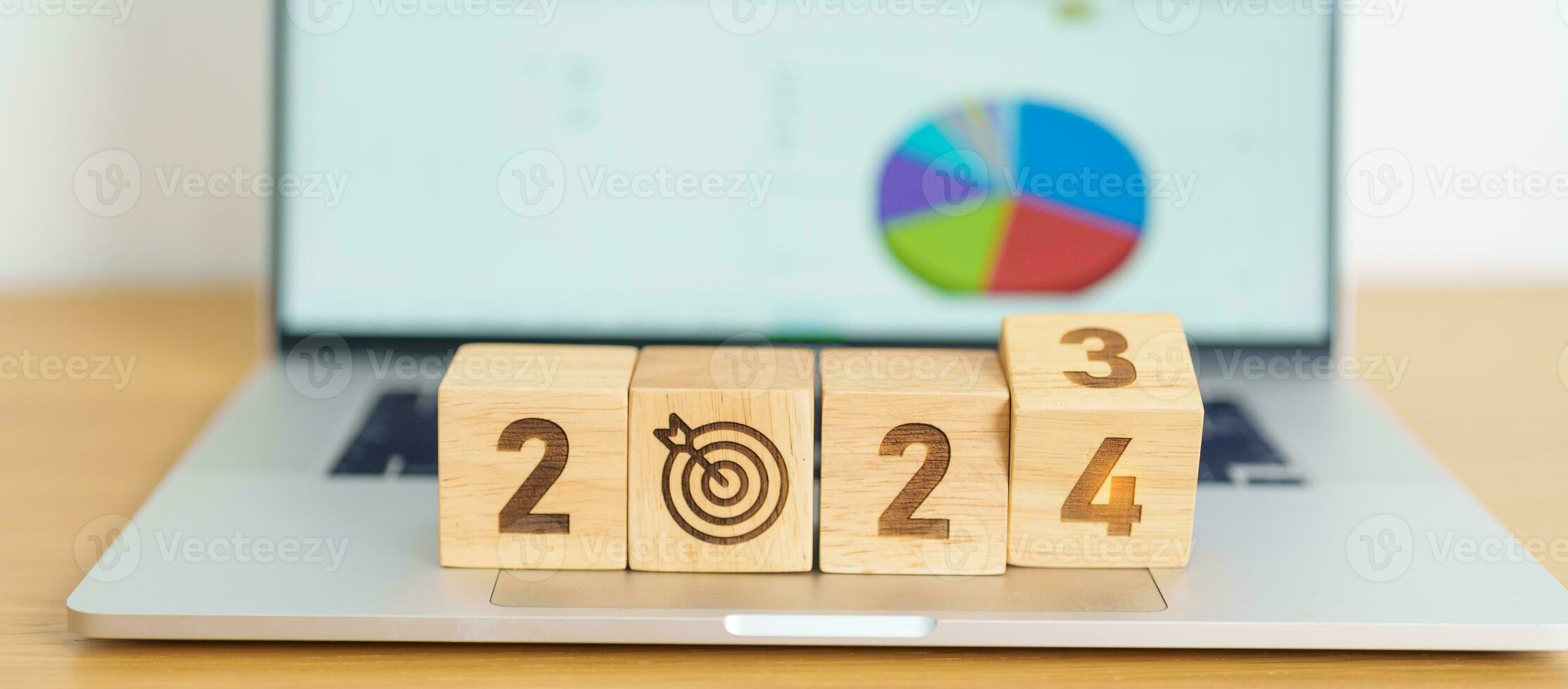 2024 Year block with dartboard icon against computer laptop background. Goal, Target, Resolution, strategy, plan, Action, mission, motivation, and New Year start concepts photo