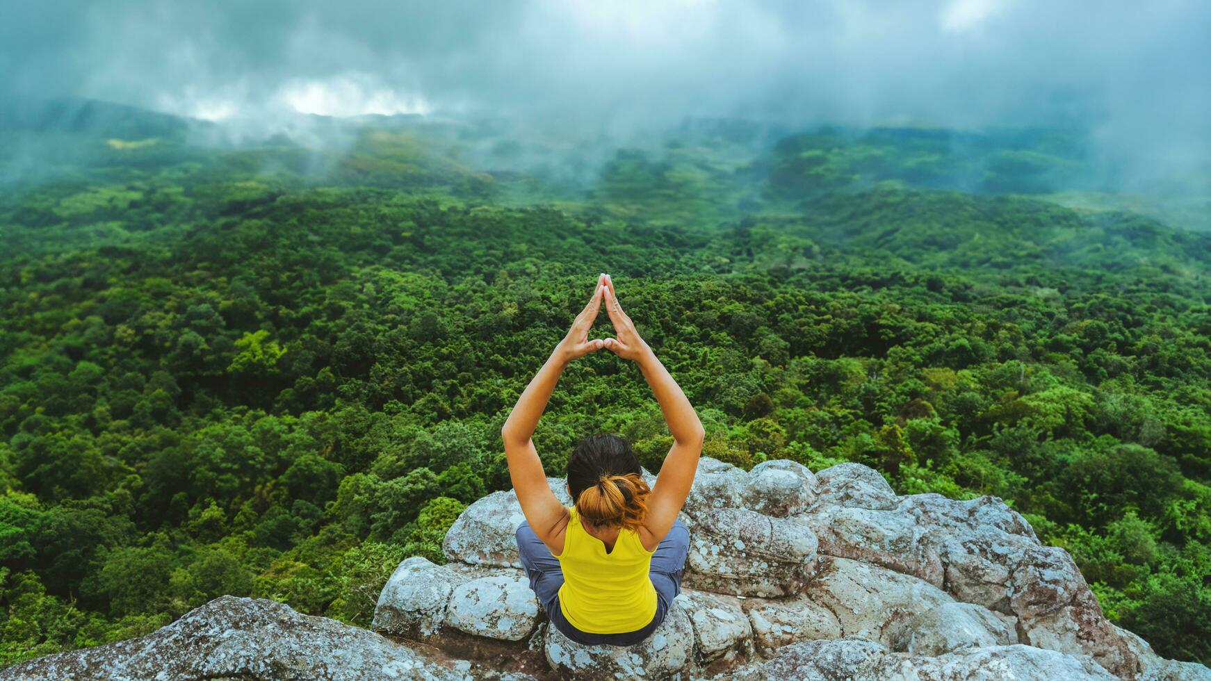 mujer asiática relajarse en las vacaciones. viajar relajarse. jugar si yoga. en el acantilado de roca de montaña. naturaleza de los bosques de montaña en tailandia foto