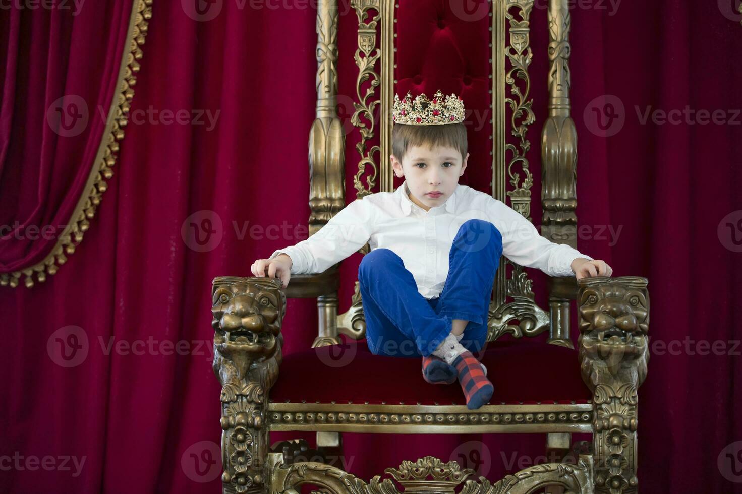 Little boy in a crown in a luxurious chair photo