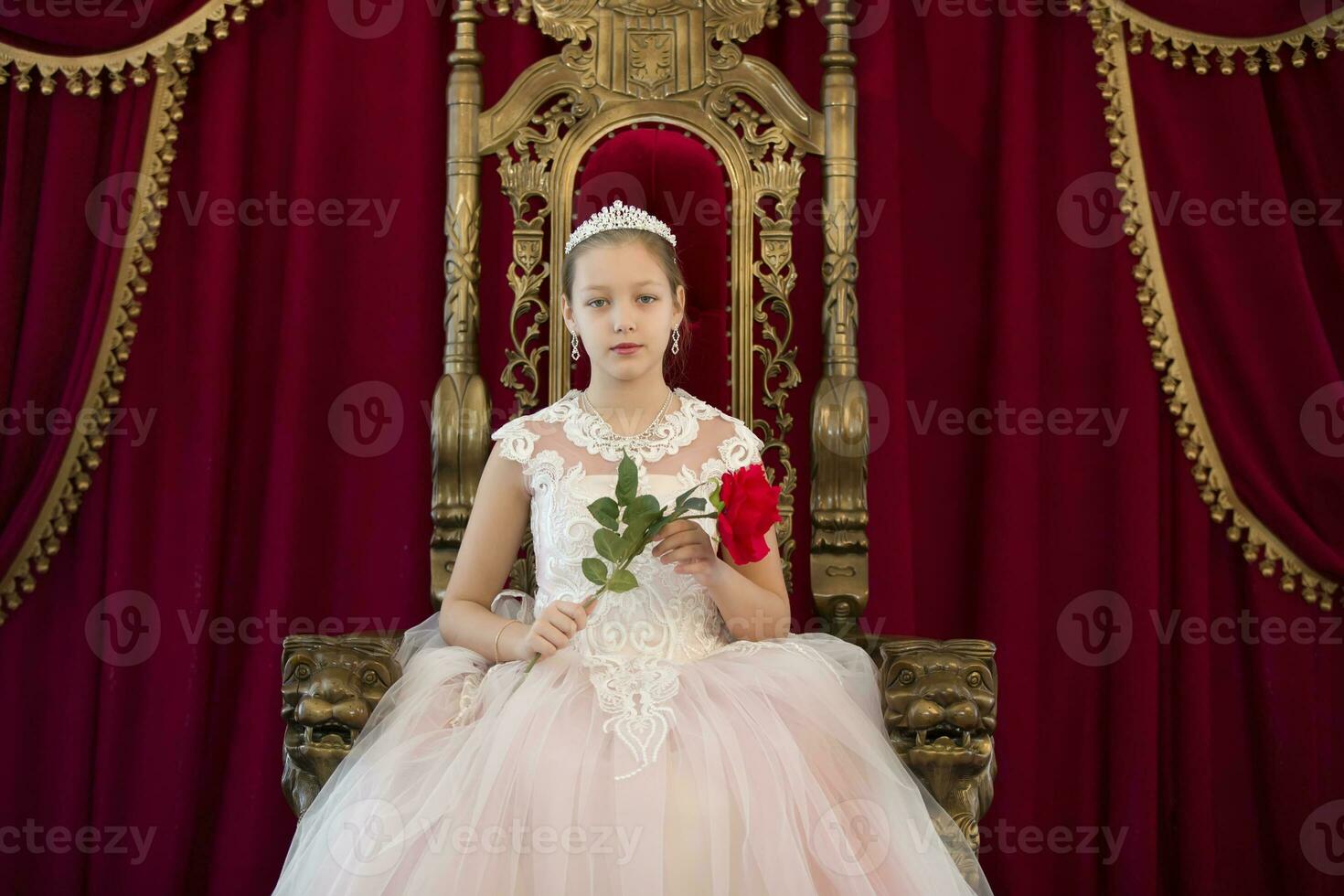 Teenager girl smart in red luxury royal armchair. Girl princess.Queen in a red chair.Luxurious young lady with a scarlet rose in a white dress in an old red armchair photo