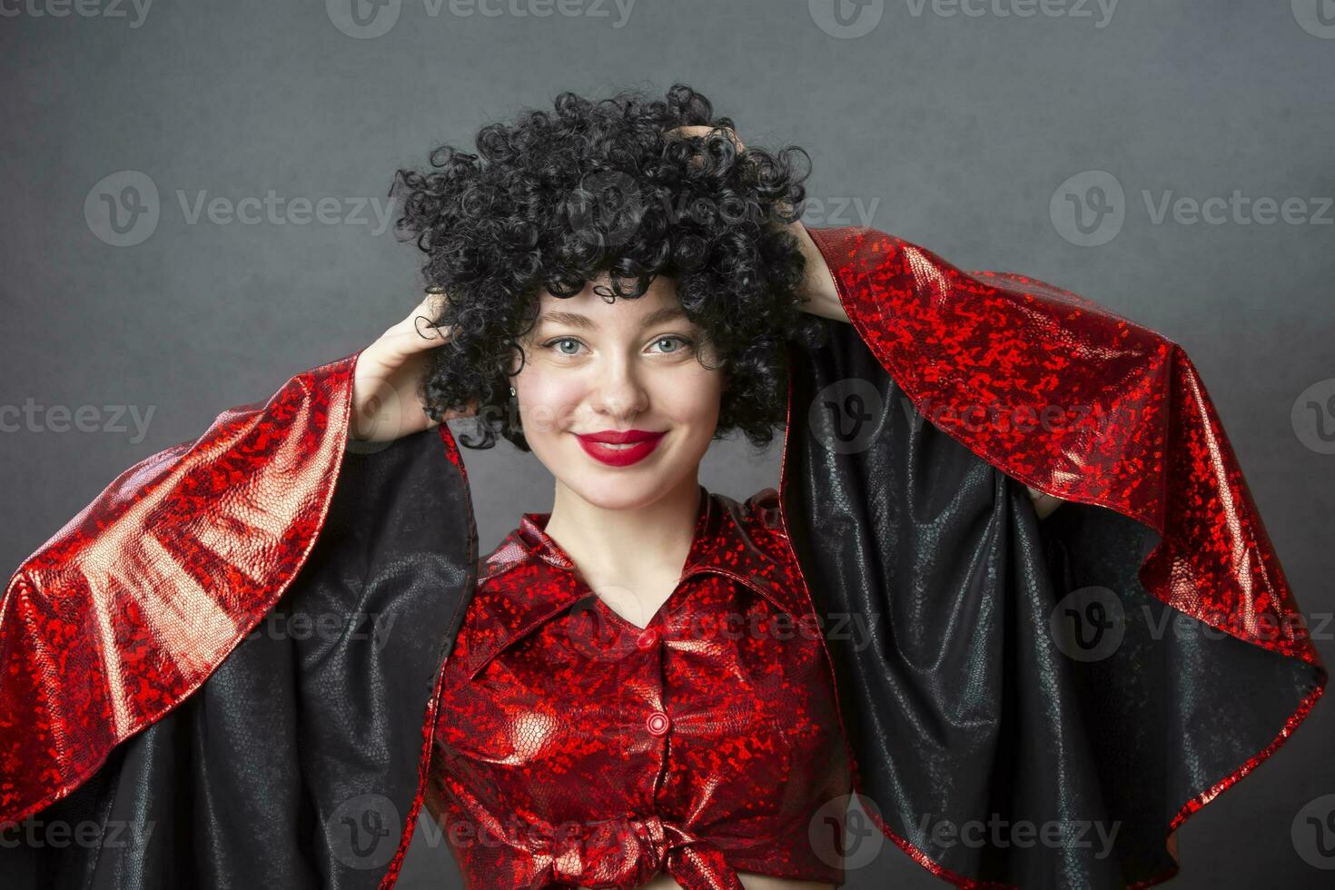 Excited woman in an afro wig on a gray background. Disco girl. photo