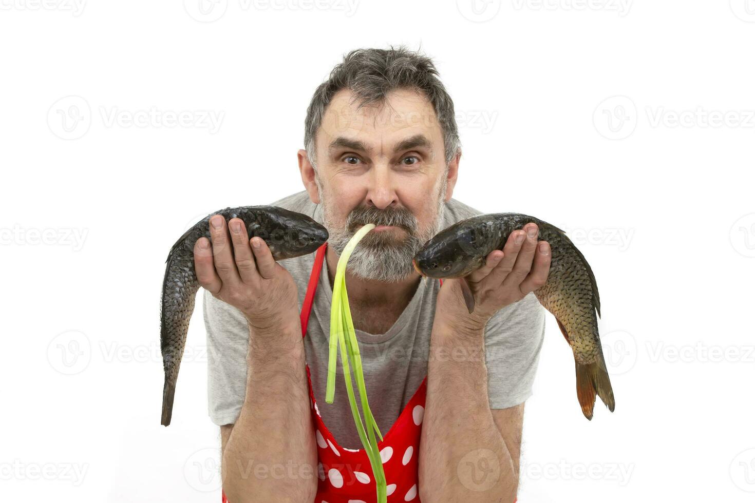 gracioso barbado pescadero en rojo delantal participación grande agua dulce pescado y mirando a cámara en blanco antecedentes foto