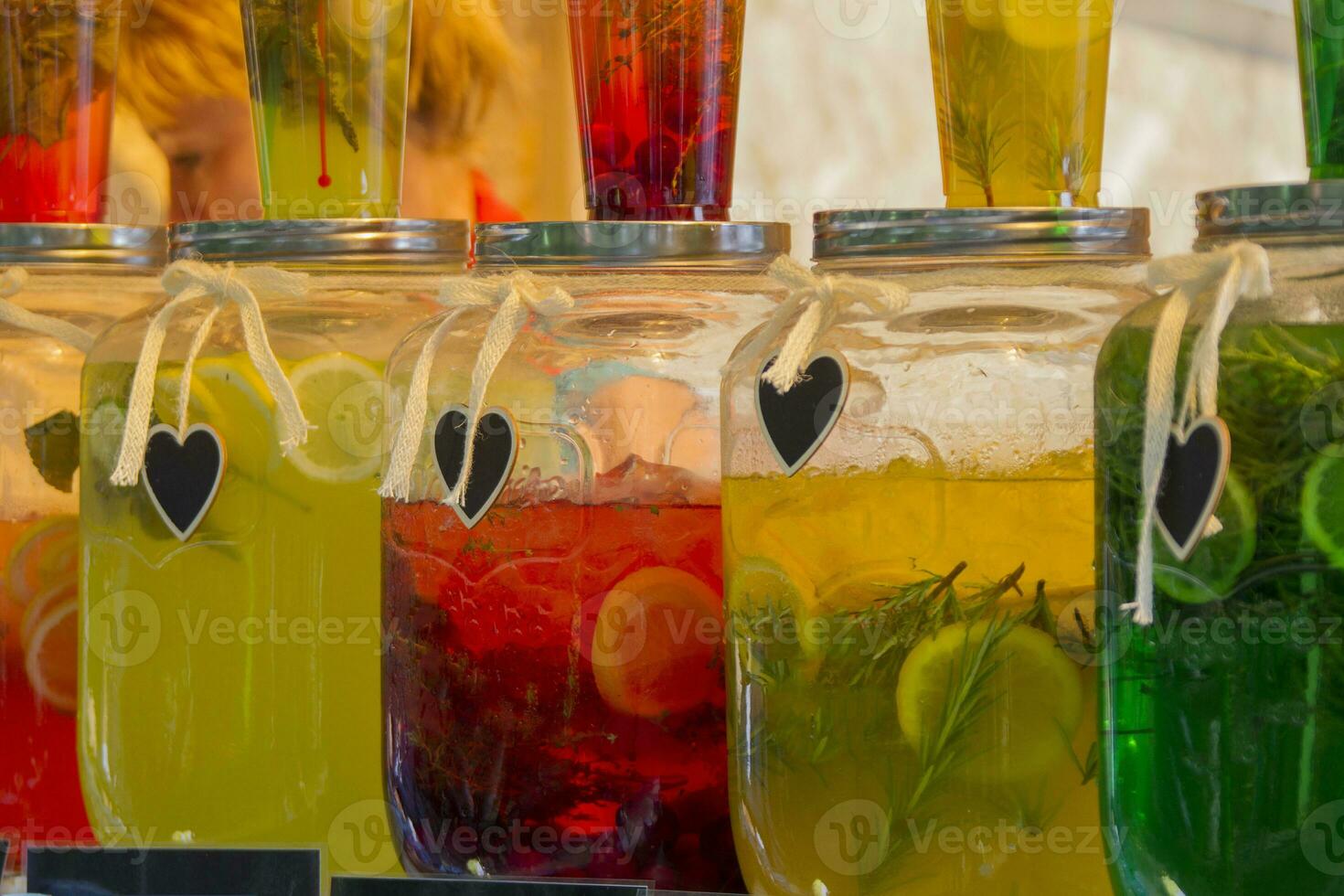 Glass jars with multi-colored lemonade. Bright summer drinks with fruits and herbs photo