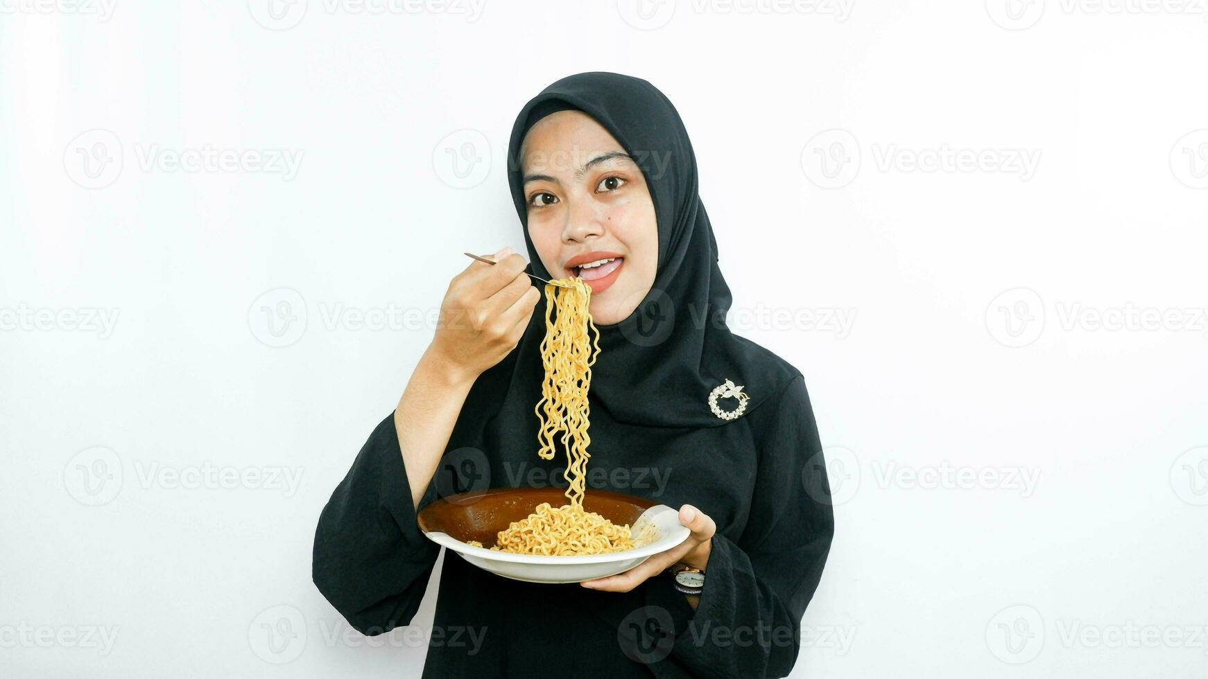 Young asian woman isolated on white background holding a plate of noodles with fork and eating it photo