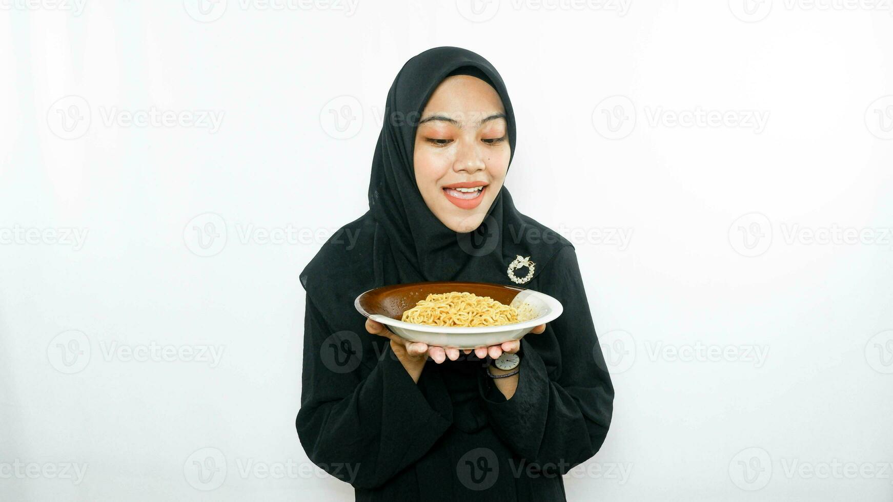 Young asian woman isolated on white background holding a plate of noodles with fork and eating it photo