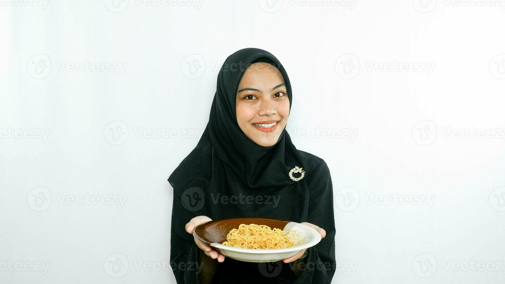 Young asian woman isolated on white background holding a plate of noodles with fork and eating it photo