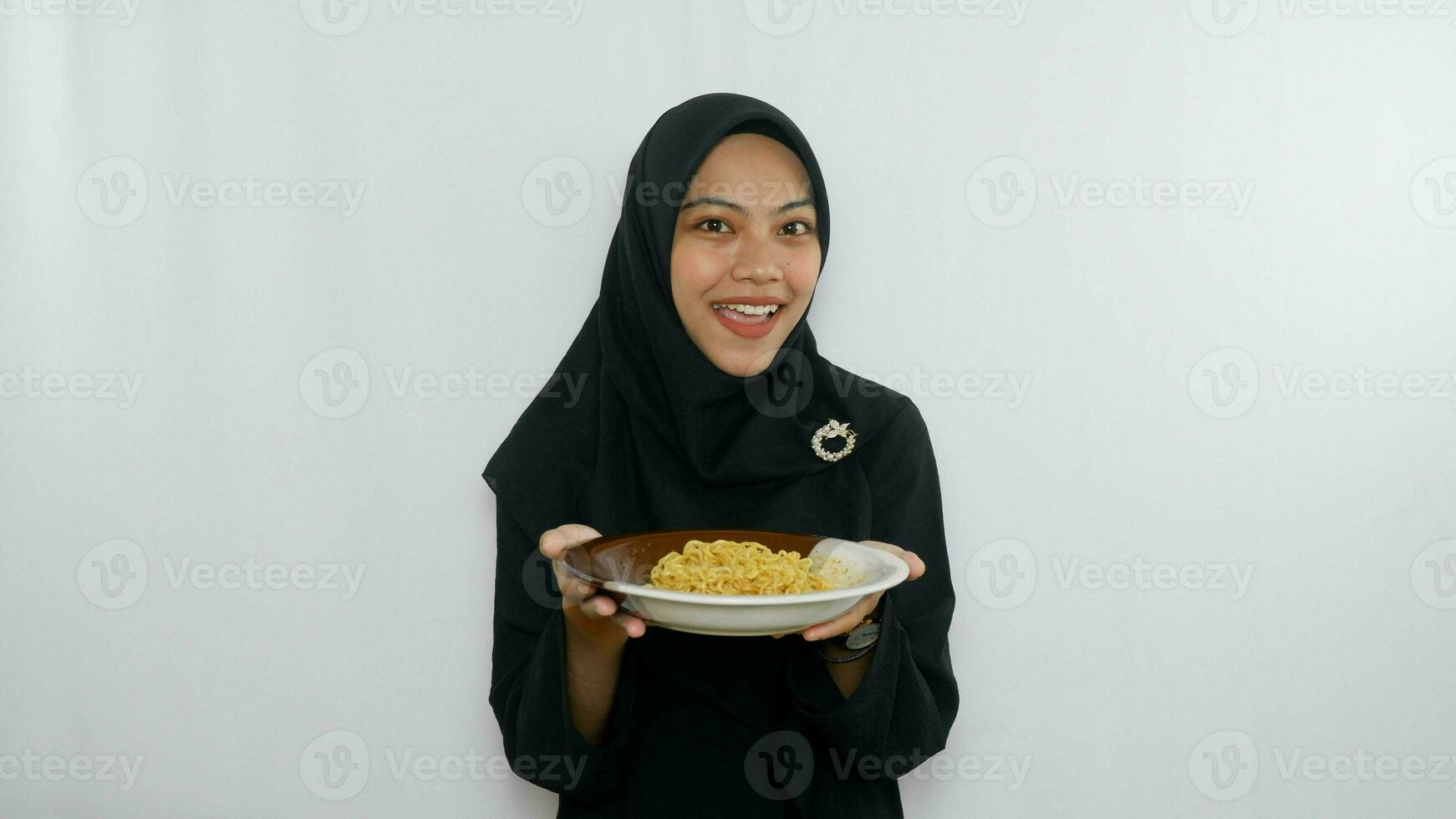 Young asian woman isolated on white background holding a plate of noodles with fork and eating it photo