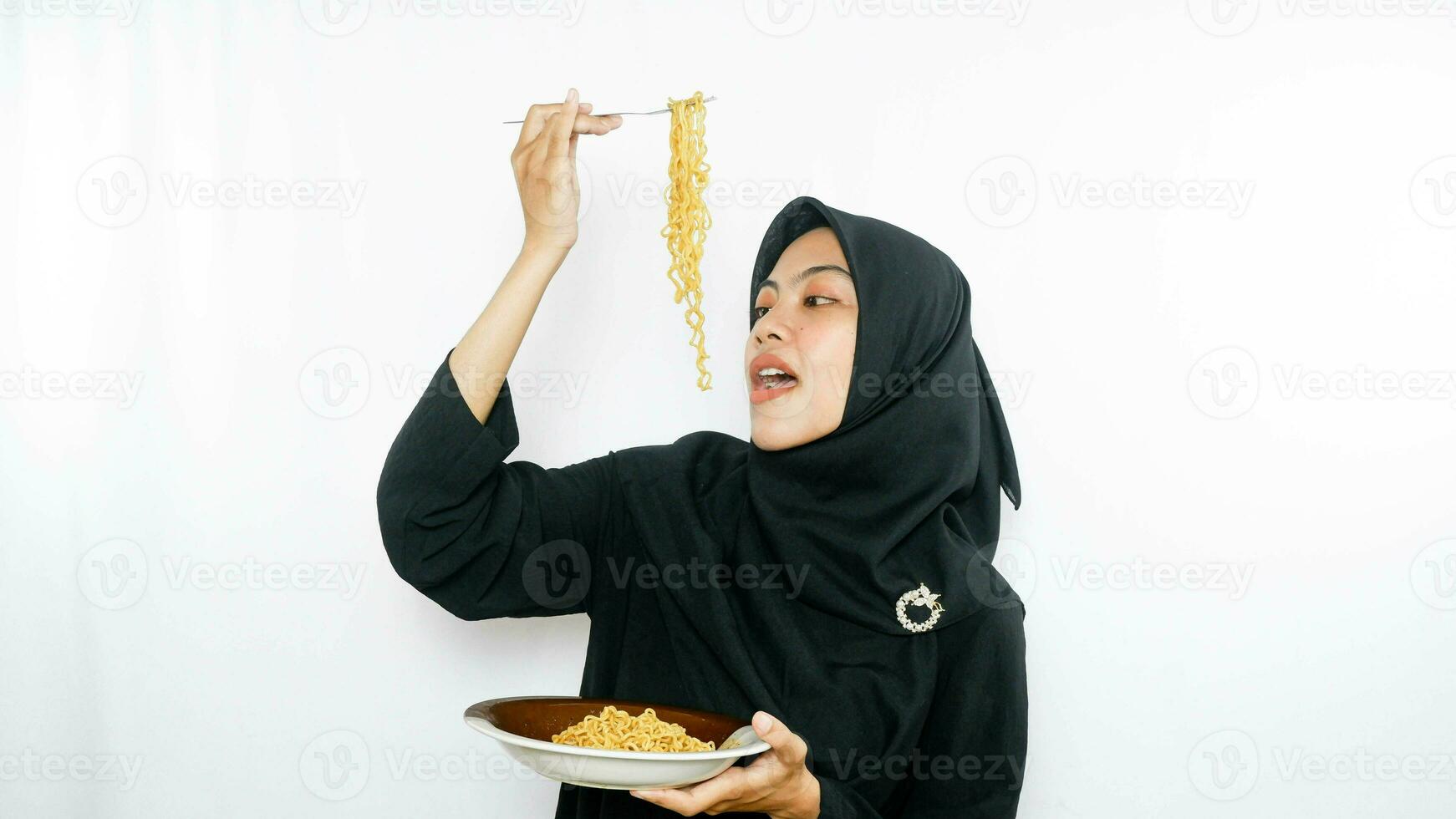 Young asian woman isolated on white background holding a plate of noodles with fork and eating it photo