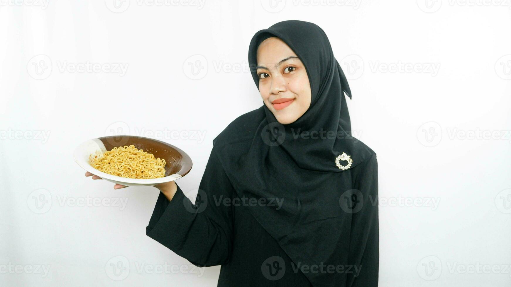 Young asian woman isolated on white background holding a plate of noodles with fork and eating it photo