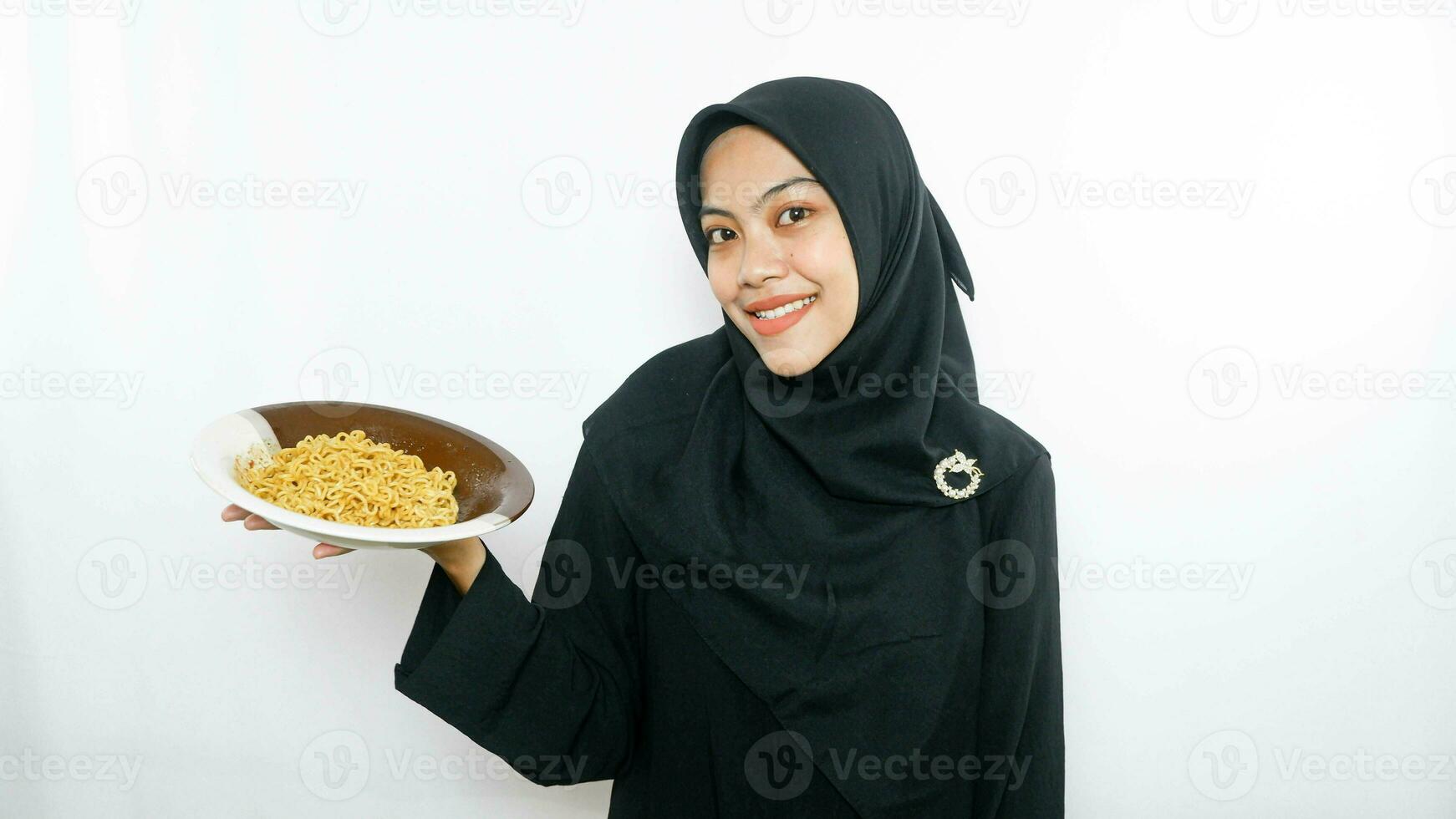 Young asian woman isolated on white background holding a plate of noodles with fork and eating it photo