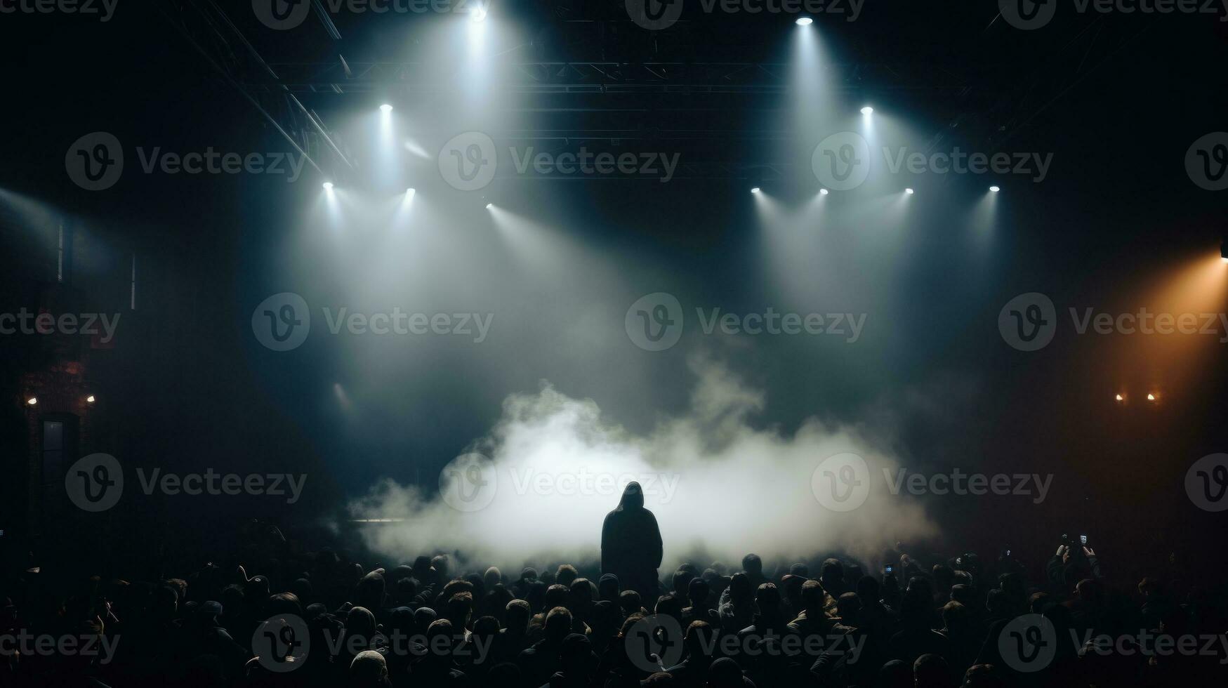 Silhouette of a scary man in hood at front of a crowd at a dark concert. photo