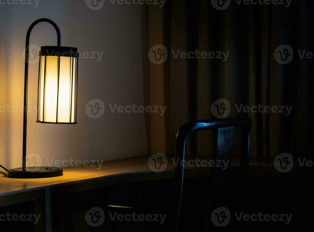 Glowing desk lamp on wooden table in the dark bedroom photo