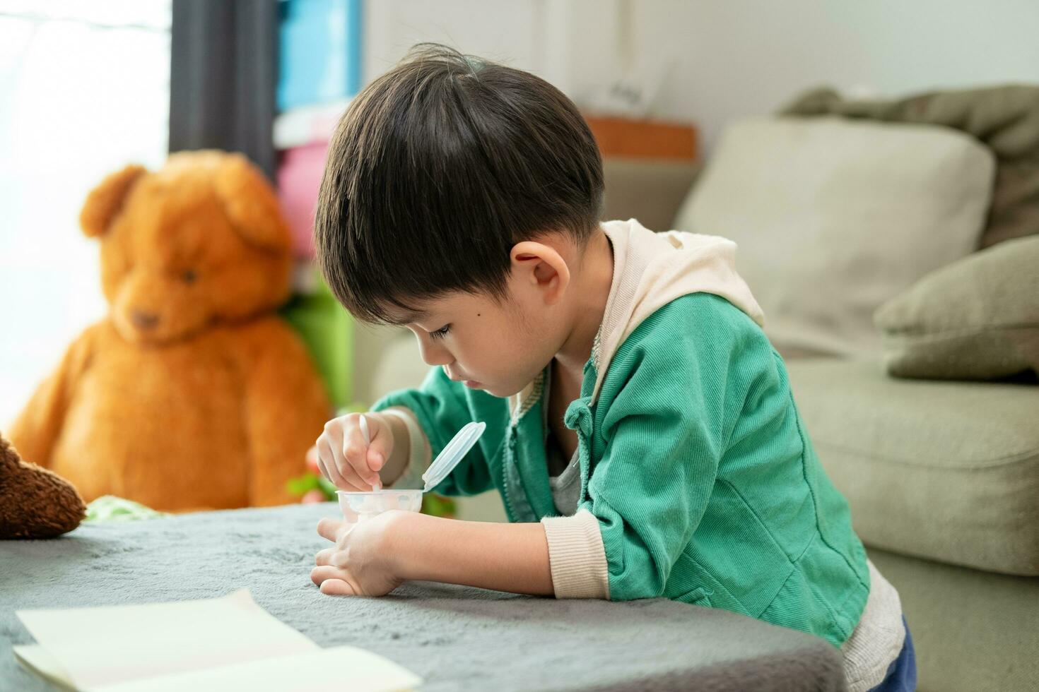 A boy happily uses a spoon to scoop up yogurt. photo