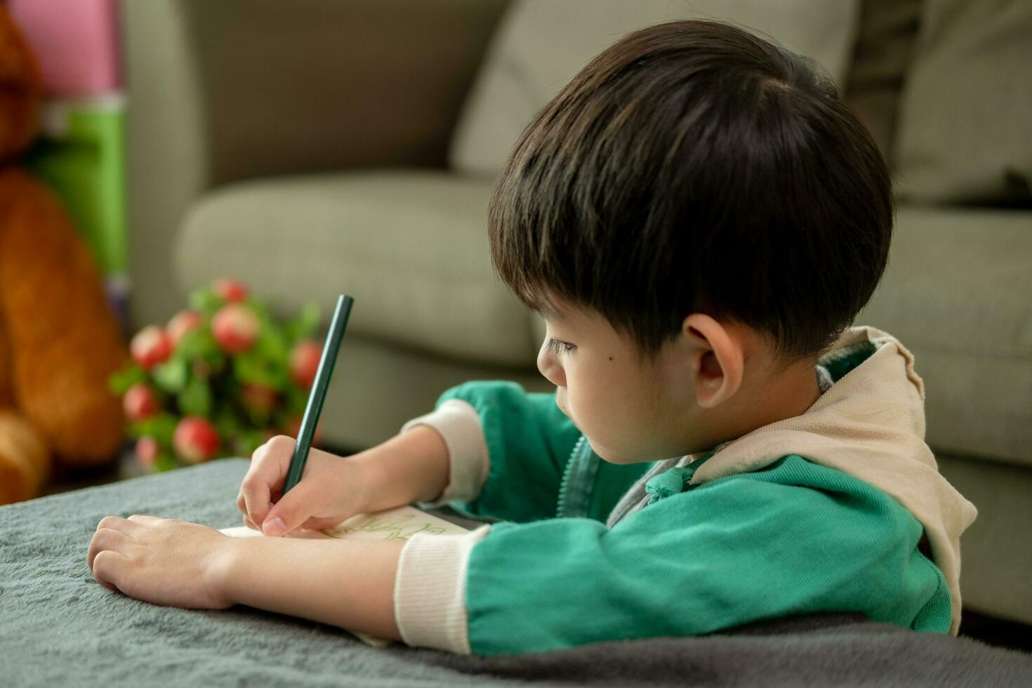 un chico es dibujo imágenes en un cuaderno en el mesa. aprendizaje fuera de el salón de clases foto