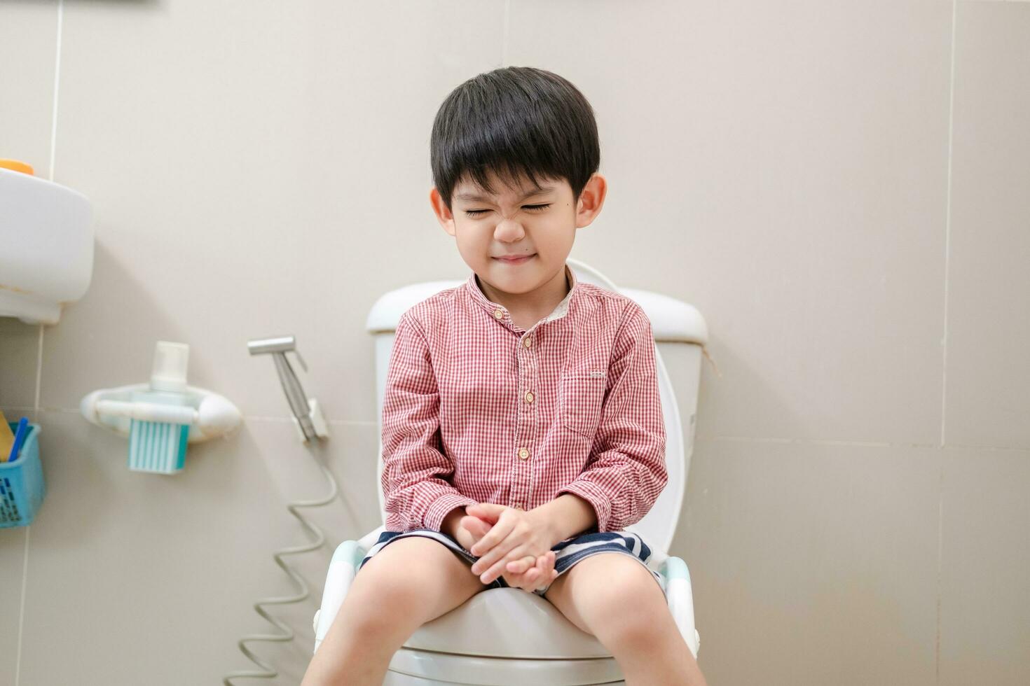 Asian boy Sitting on the toilet bowl in hand holding tissue photo