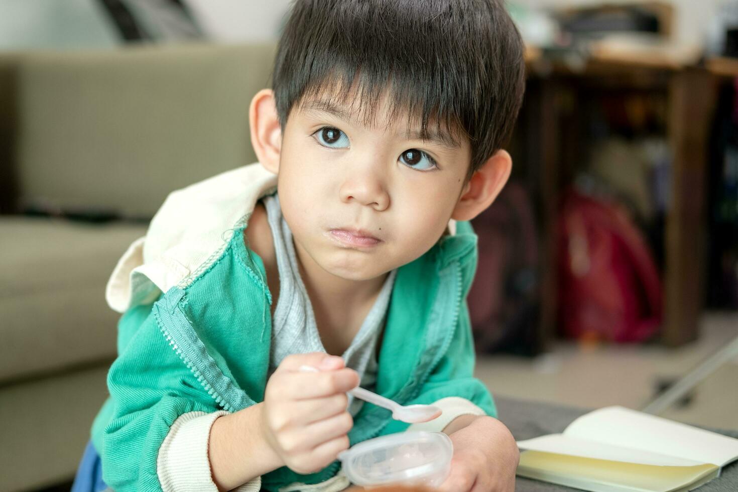 A boy happily uses a spoon to scoop up yogurt. photo