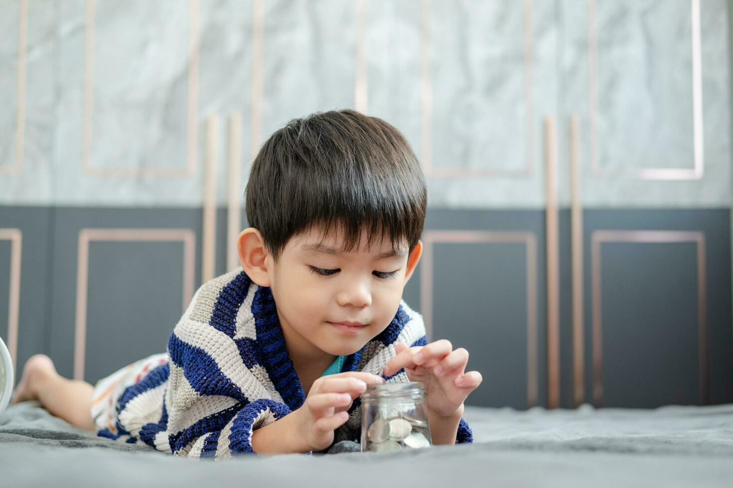 asiático chico felizmente contando monedas a salvar dinero foto