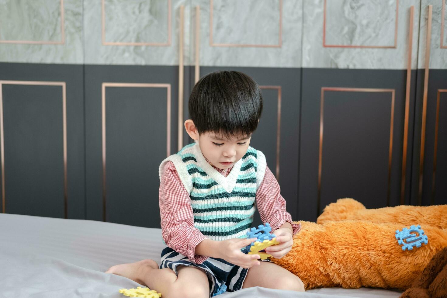 Asian boy playing with jigsaw puzzles on the bed joyfully photo