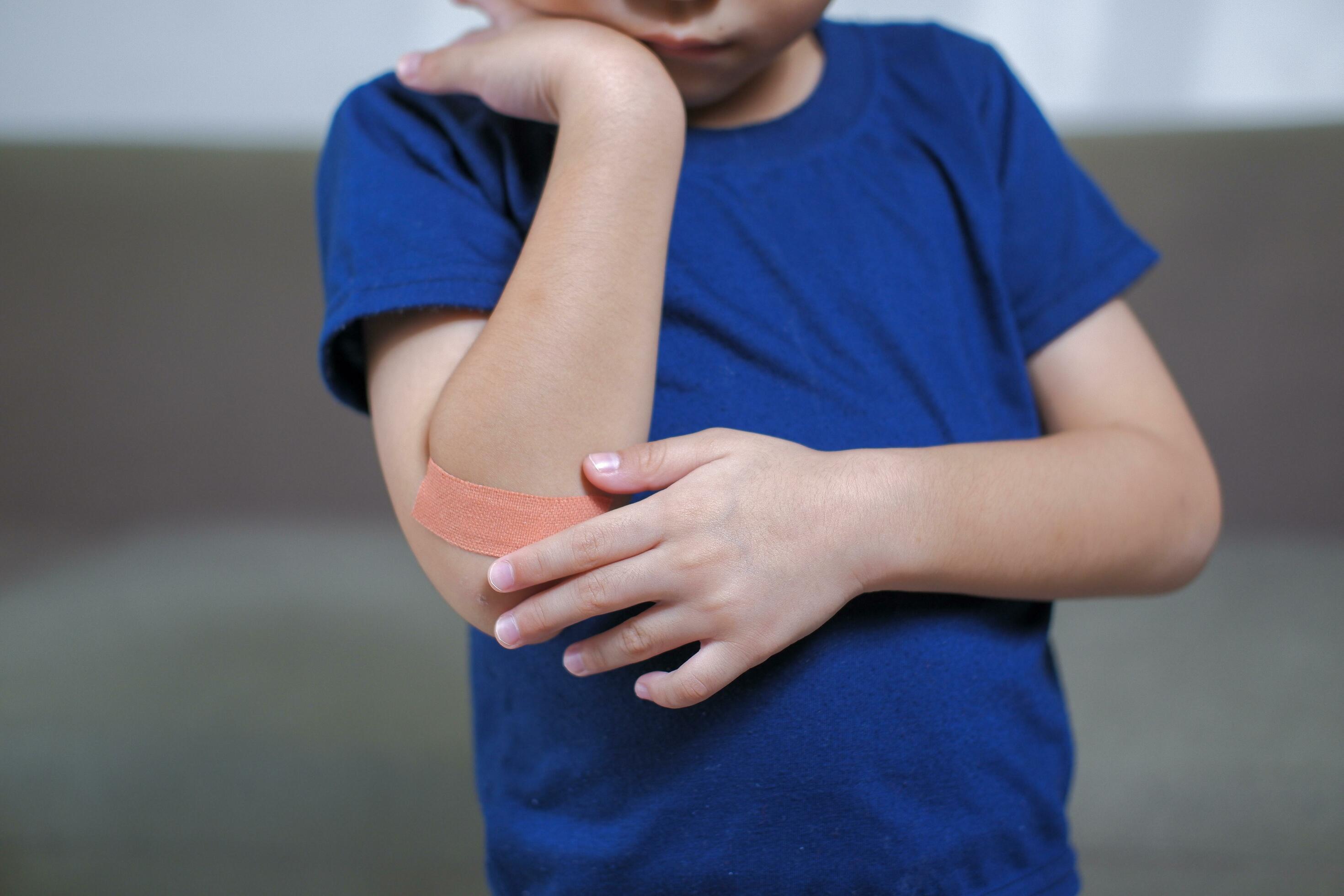 A boy hurts his arm, holding his bandaged arm. 32475780 Stock Photo at