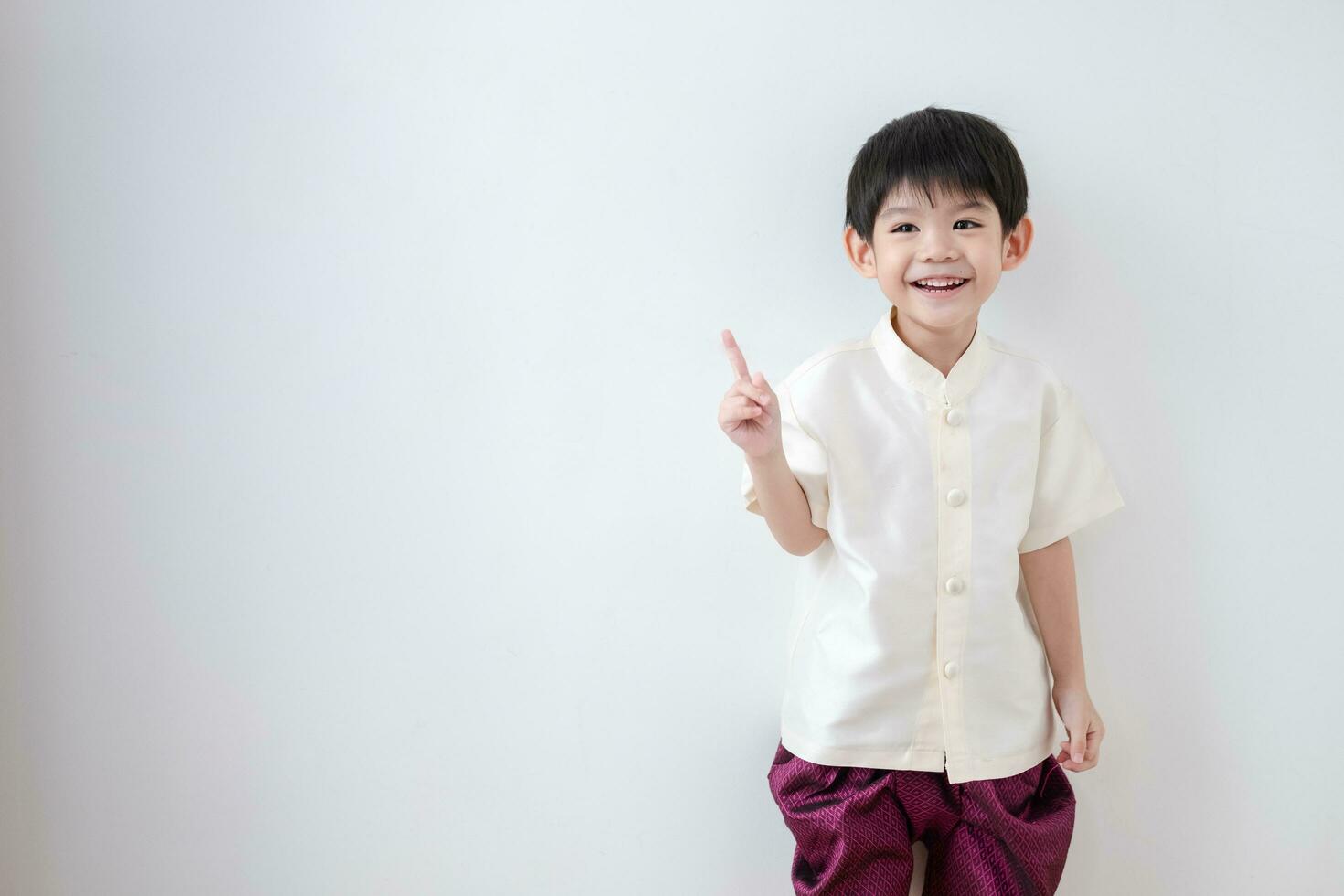 Asian boy Wearing traditional Thai clothing, standing with index finger upwards. on a white background photo