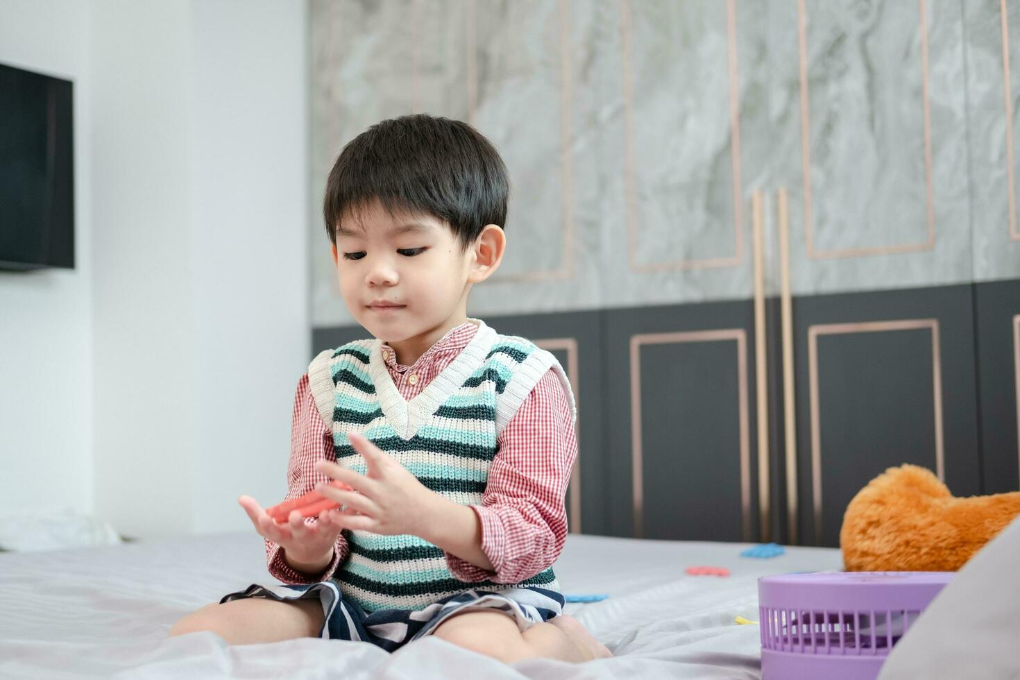 Asian boy playing with jigsaw puzzles on the bed joyfully photo