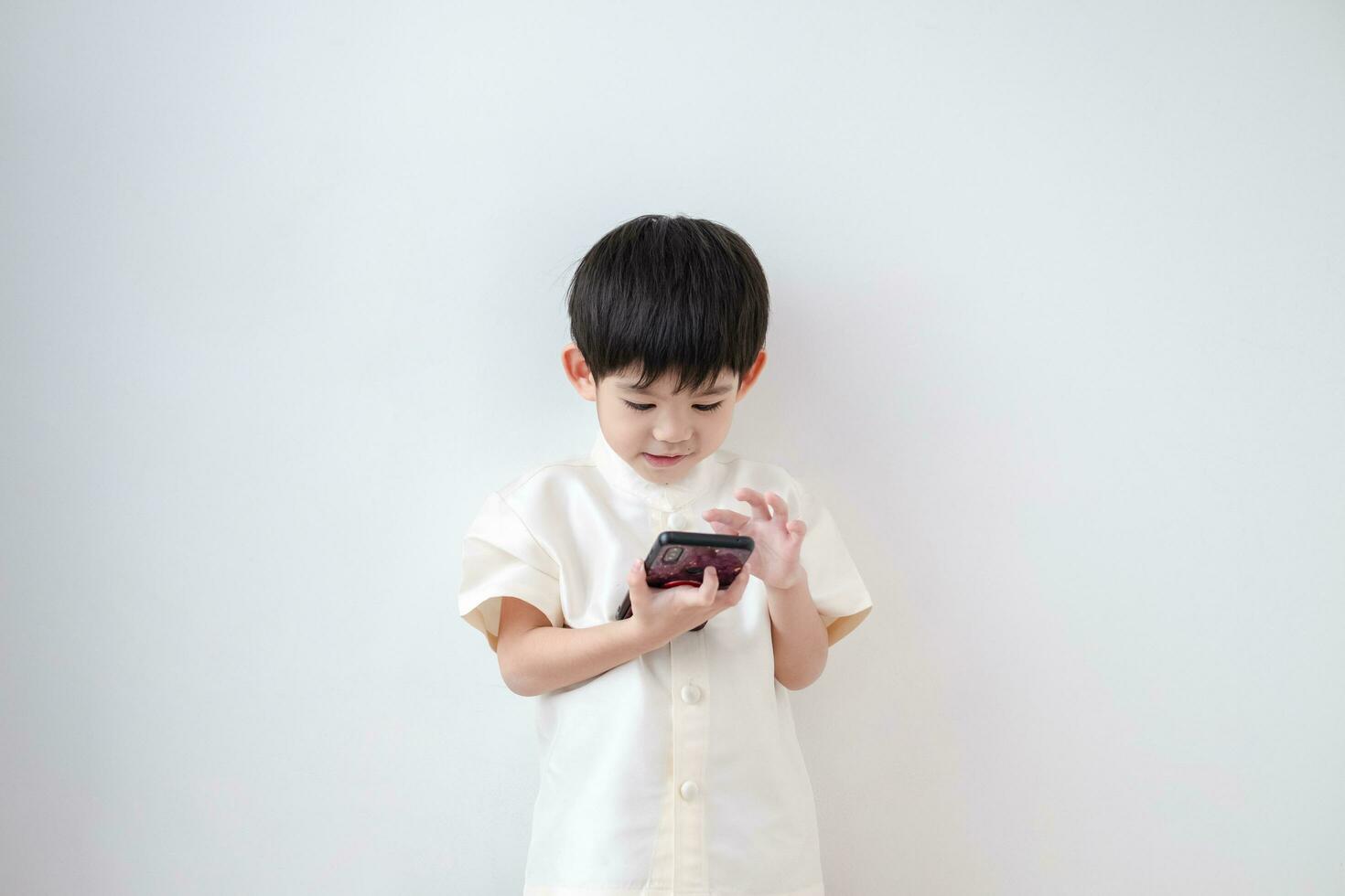 Asian boy Wear traditional Thai clothing play with mobile phone on a white background photo