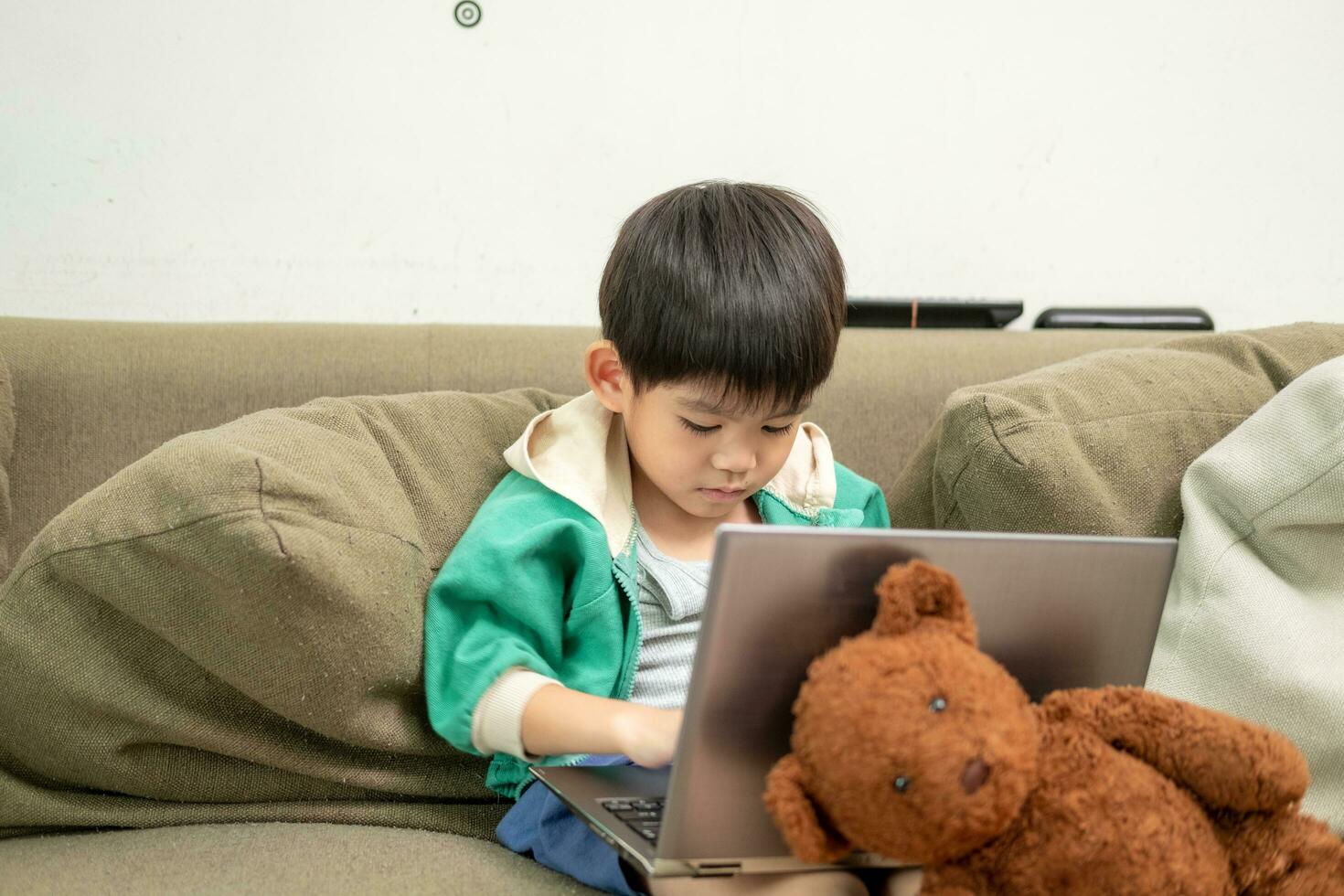 Asian boy studying online and doing activities on laptop photo