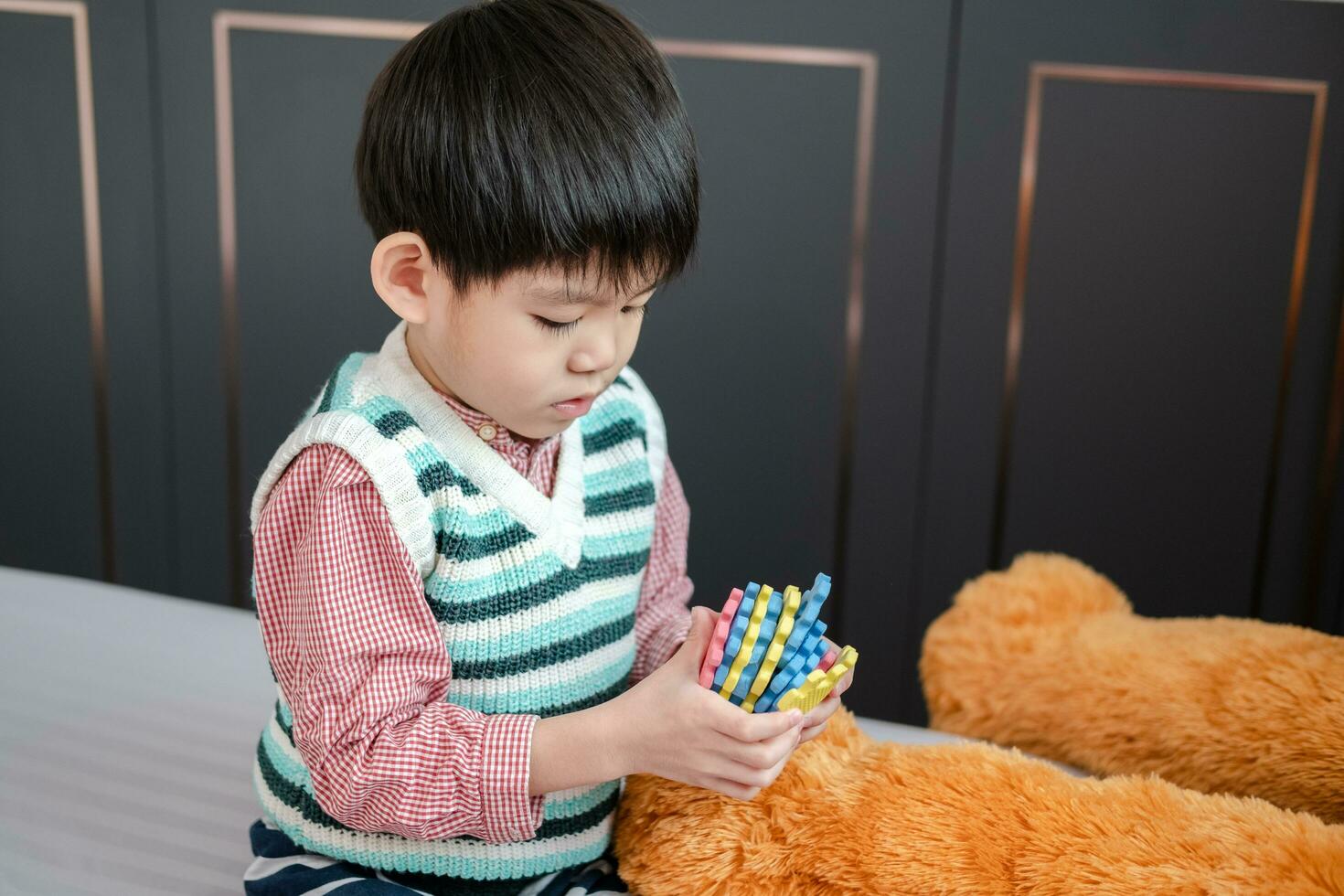 Asian boy playing with jigsaw puzzles on the bed joyfully photo