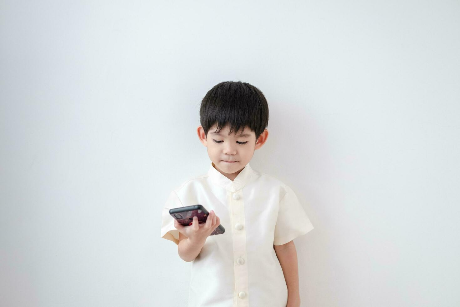 Asian boy Wear traditional Thai clothing play with mobile phone on a white background photo