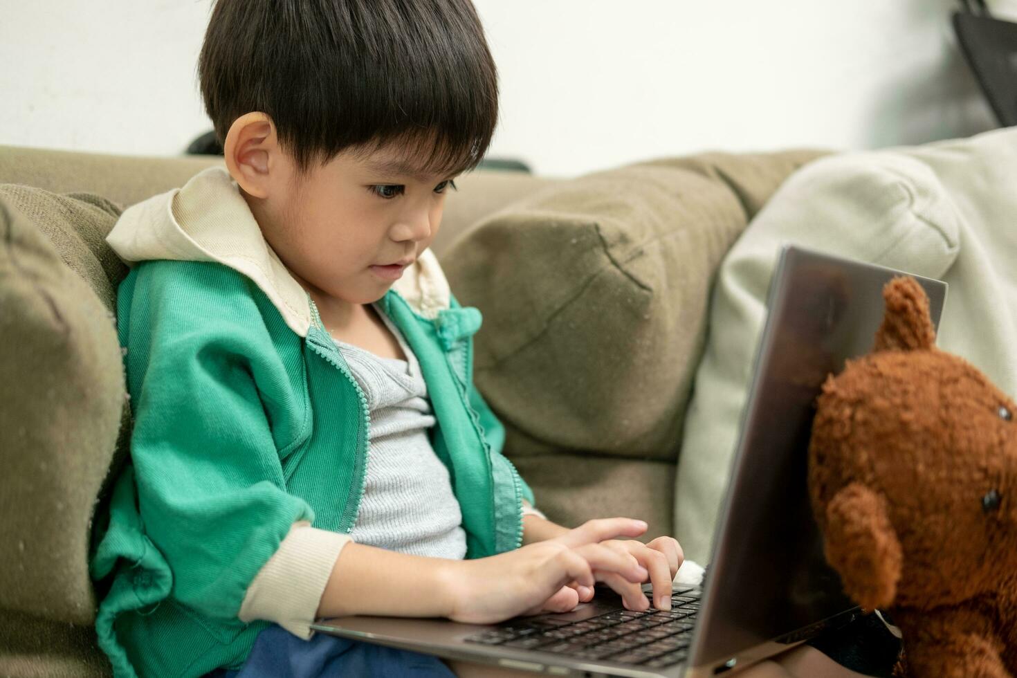 Asian boy studying online and doing activities on laptop photo