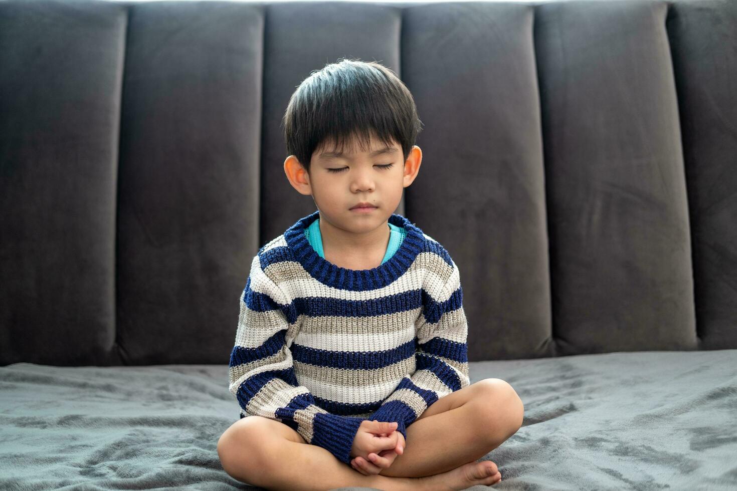 Asian boy doing meditation pose or yoga for kids photo