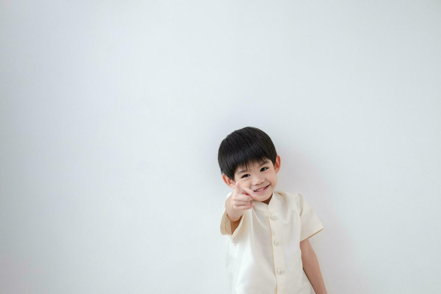 Asian boy Wearing traditional Thai clothing, standing with index finger forward. on a white background photo