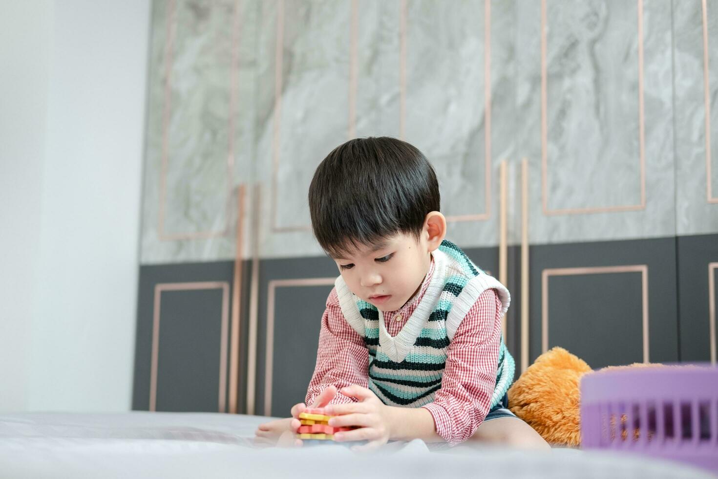 Asian boy playing with jigsaw puzzles on the bed joyfully photo