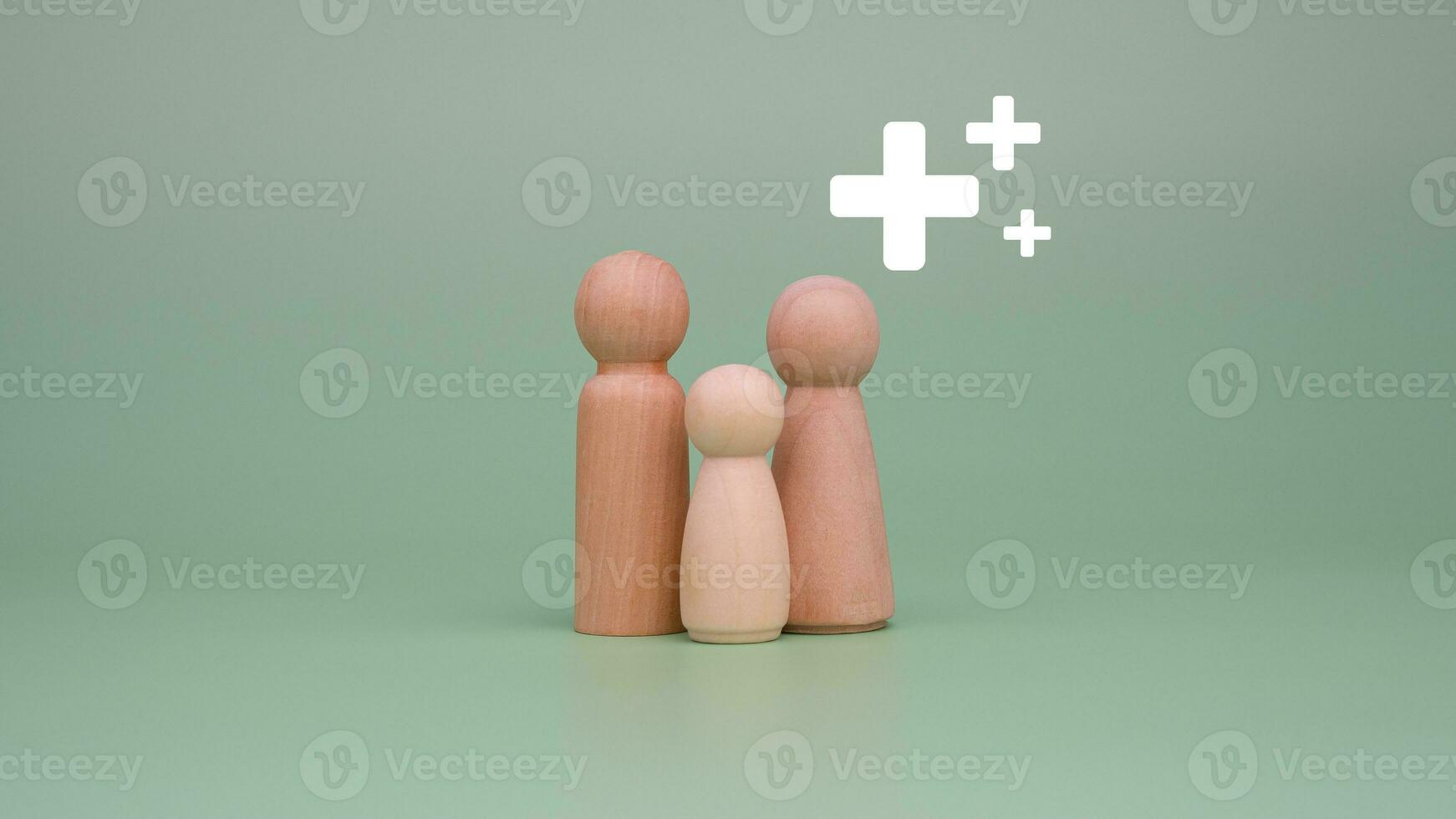 The concept of health insurance and medical welfare. Family of model wooden doll and plus sign on a green background. Health insurance and access to health care. health care planning photo