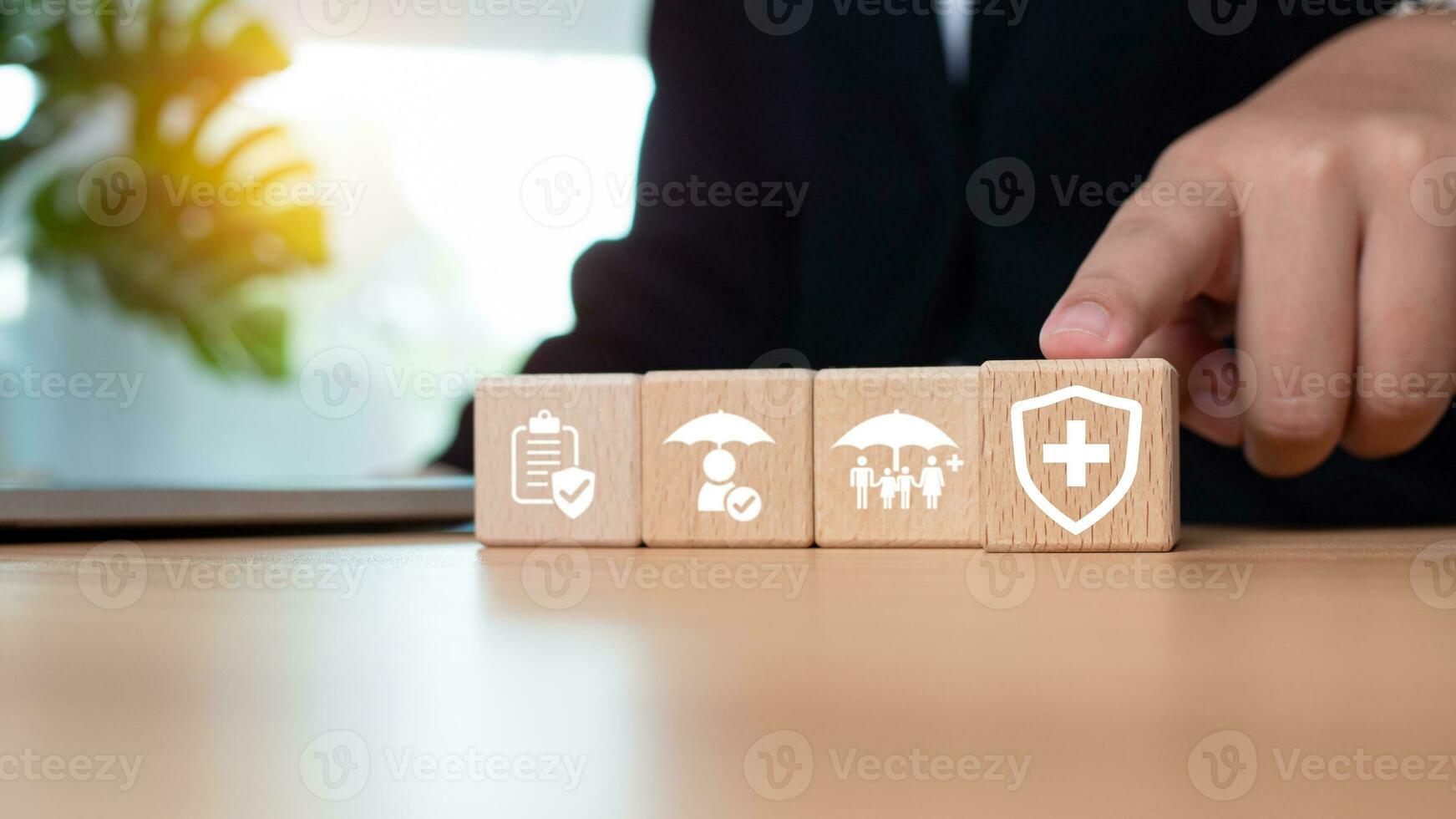 Businessman points his finger at a wooden block printed with insurance icons representing the concept of health insurance and medical benefits and healthcare planning. photo