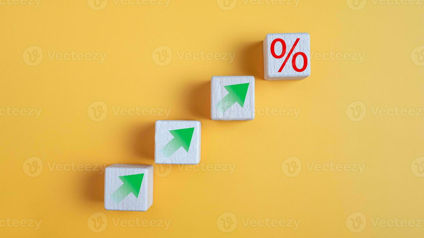Wooden block with percentage symbol and up arrow on yellow background. Interest rate and dividend concept,  return on stocks and mutual funds, long term investment for retirement. photo