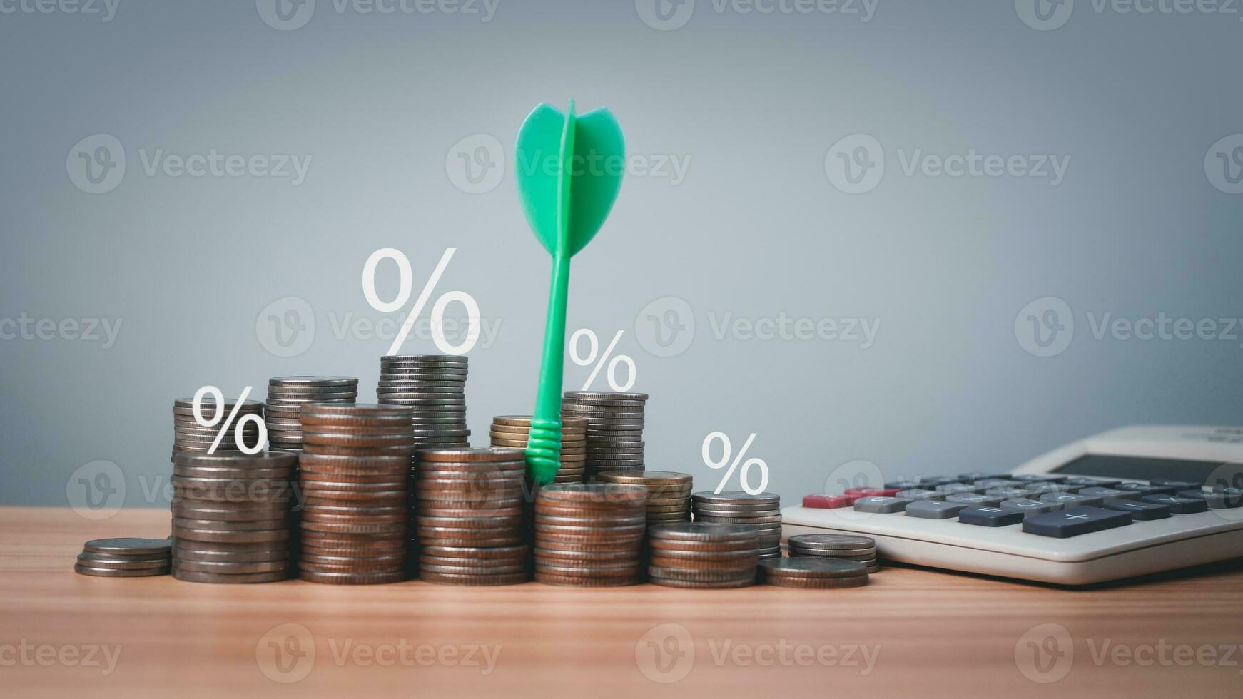 The green arrow hits the target in the center of a row of coins and calculator on the wooden floor. Concepts of finance, savings and investment. Business growth concept, finance goals concept. photo