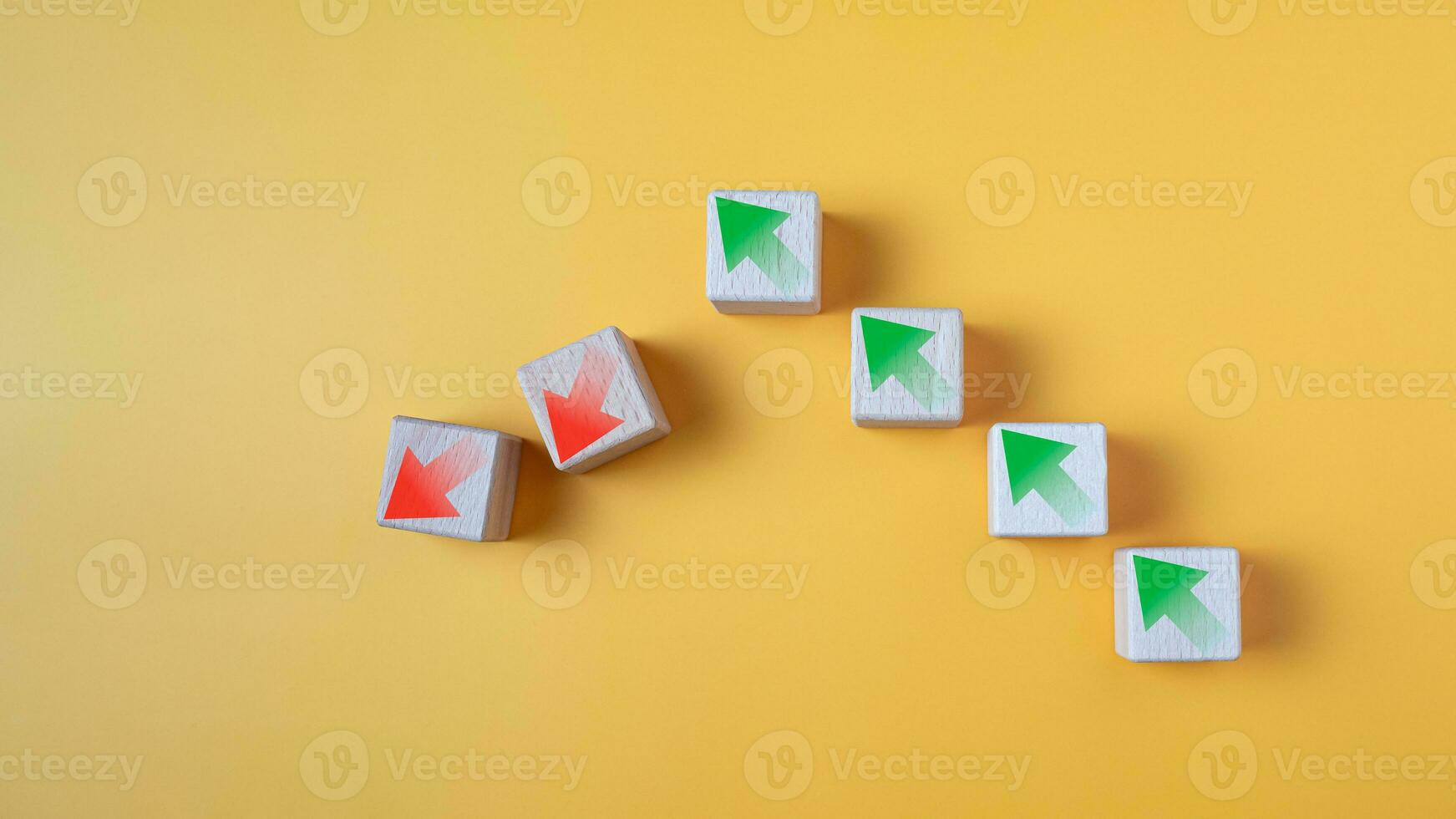Green arrow and red arrow on wooden block represents economy trending downwards on yellow background. Economy recession crisis, inflation, stagflation, business and financial loss concept. photo