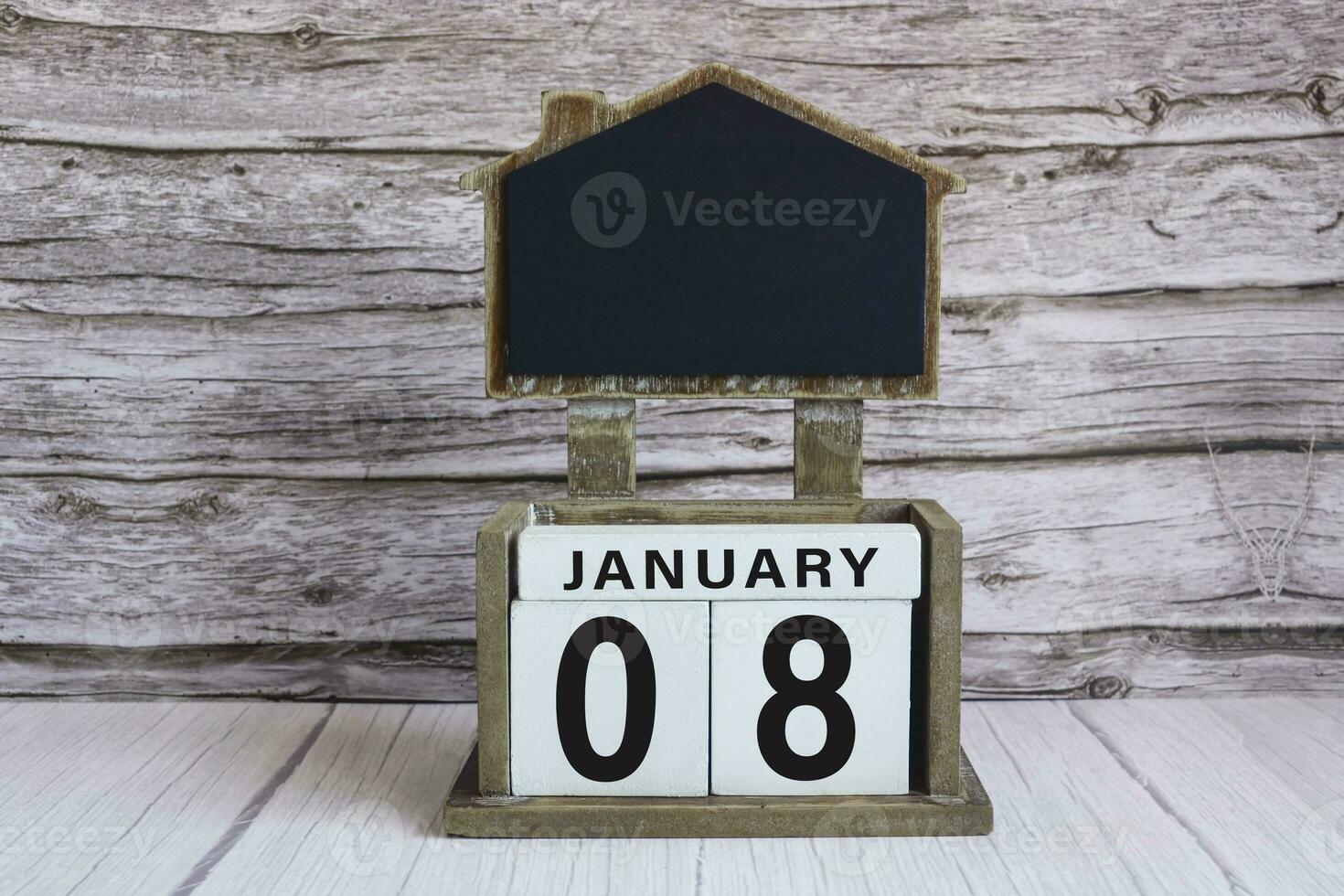Chalkboard with January 08 date on white cube block on wooden table. photo