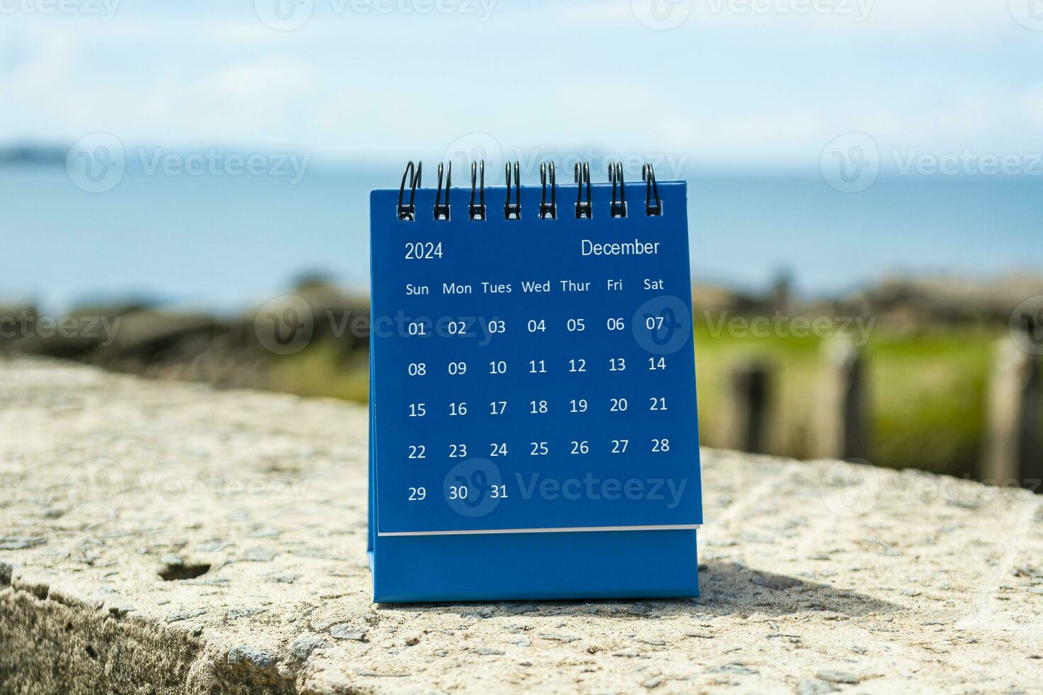 Blue December 2024 calendar on blurred background of blue ocean. photo