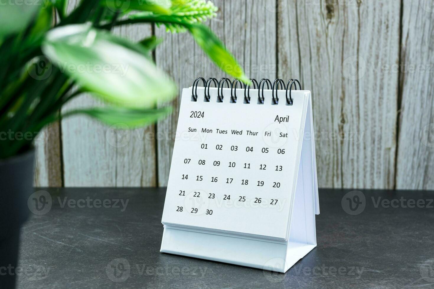 White April 2024 calendar on wooden desk. 2024 New Year Concept photo