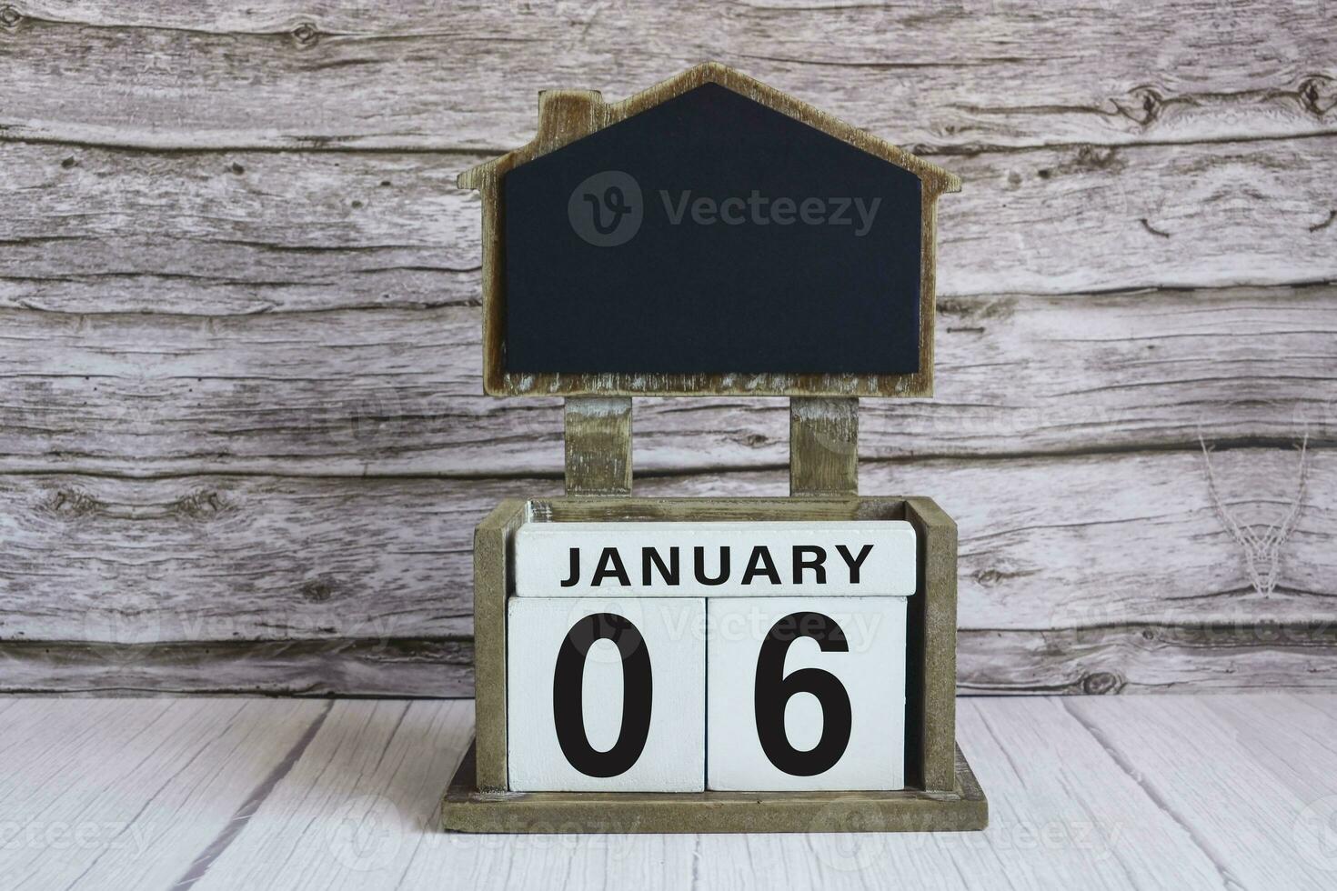 Chalkboard with January 06 date on white cube block on wooden table. photo