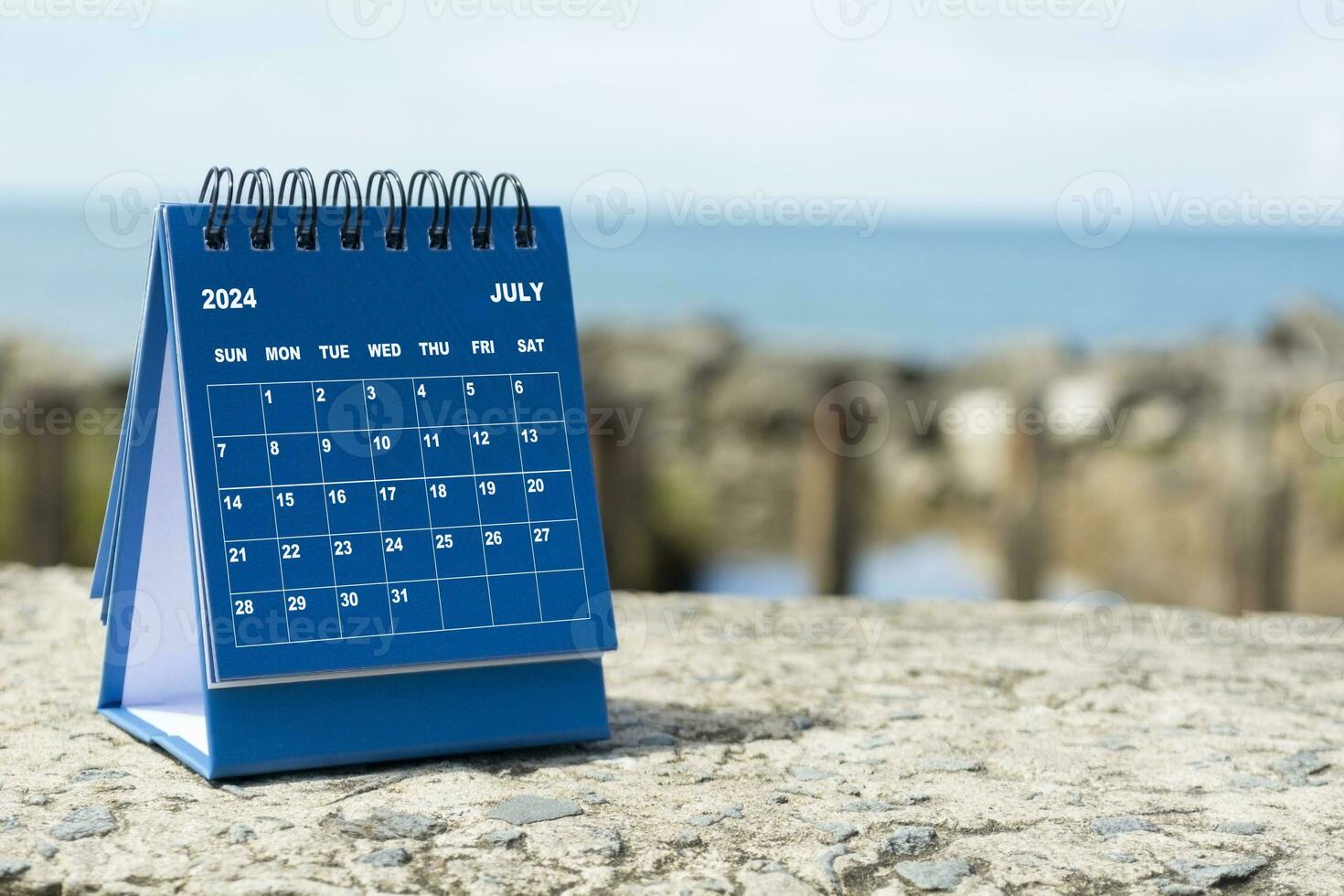 Blue July 2024 calendar on blurred background of blue ocean. New Year 