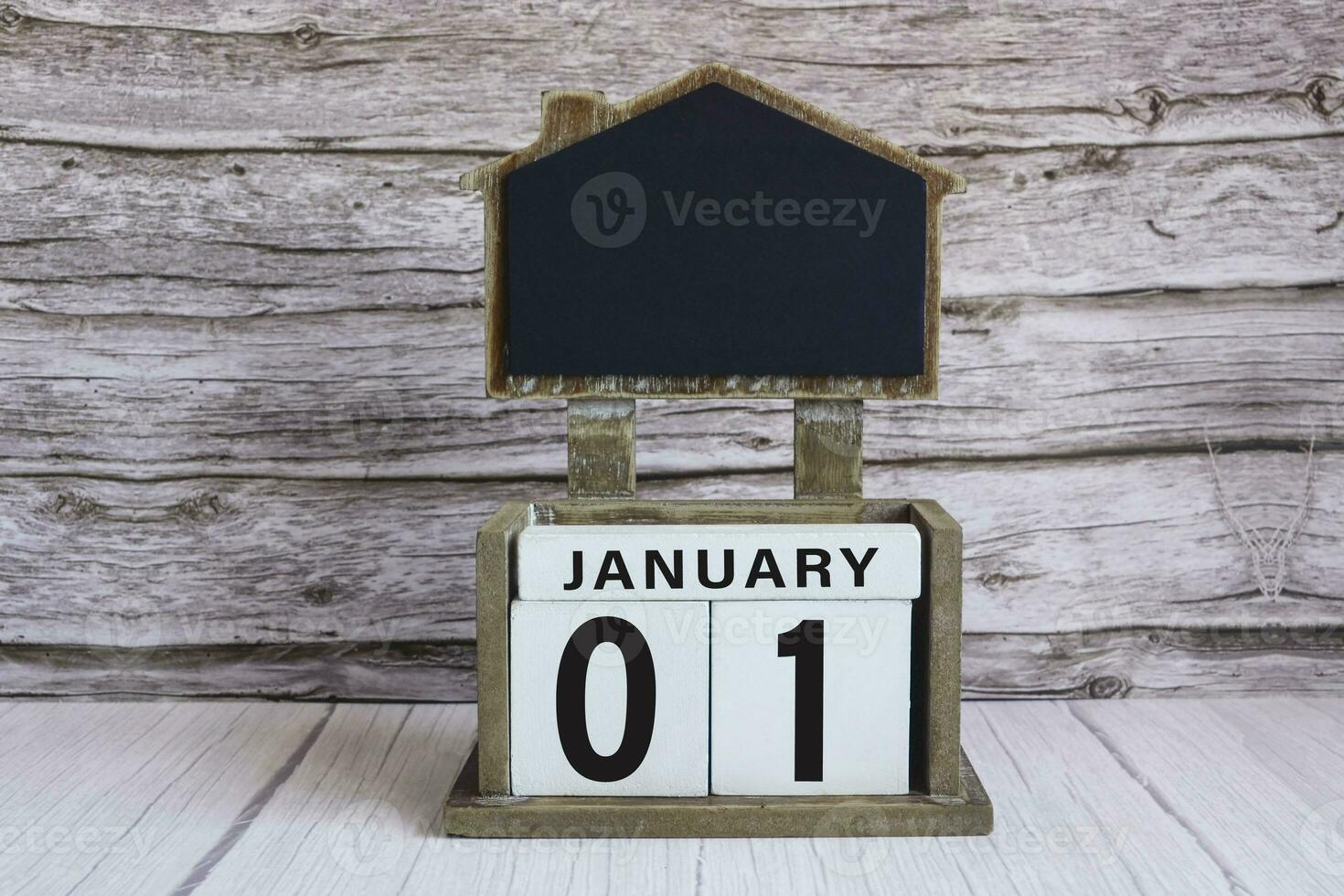 Chalkboard with January 01 date on white cube block on wooden table. photo
