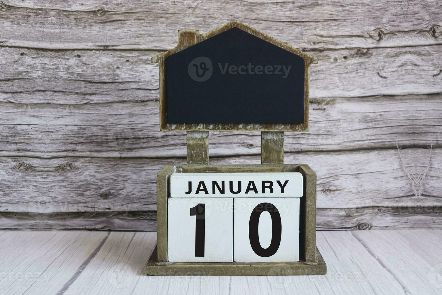 Chalkboard with January 10 date on white cube block on wooden table. photo